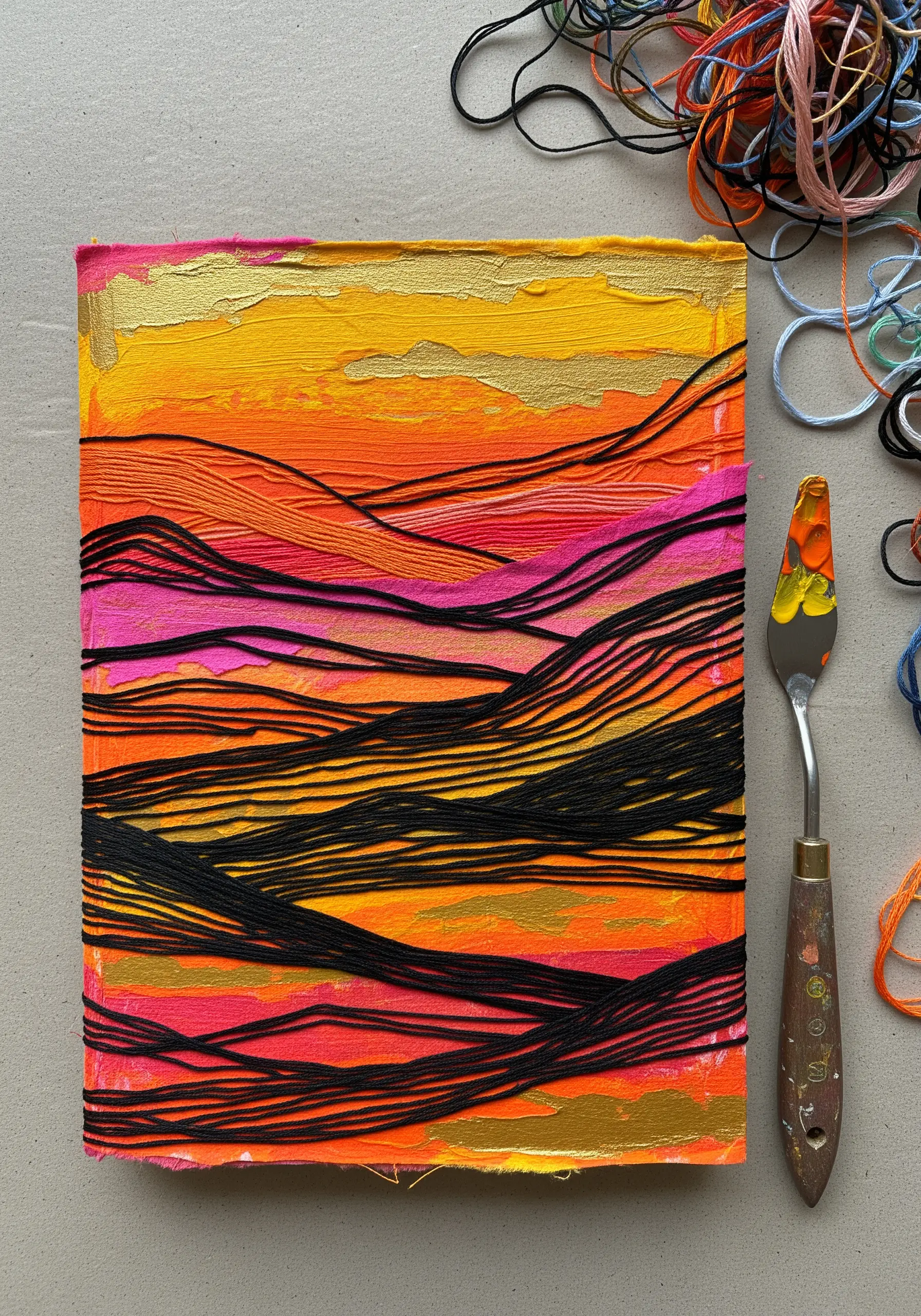 Abstract landscape on a journal cover made with wrapped black thread over textured orange paint.
