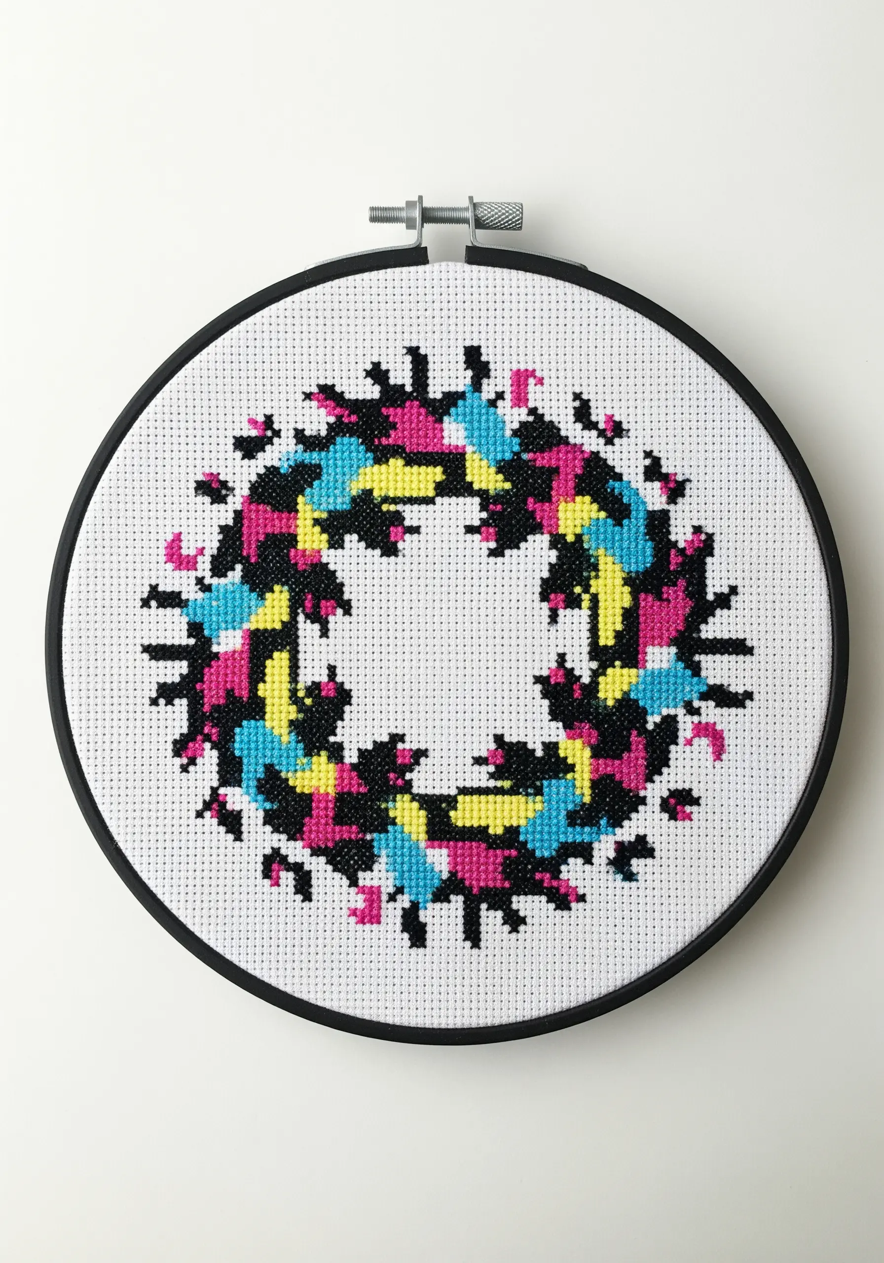 A cross-stitched abstract wreath in a CMYK color palette, creating a pixelated, modern look.