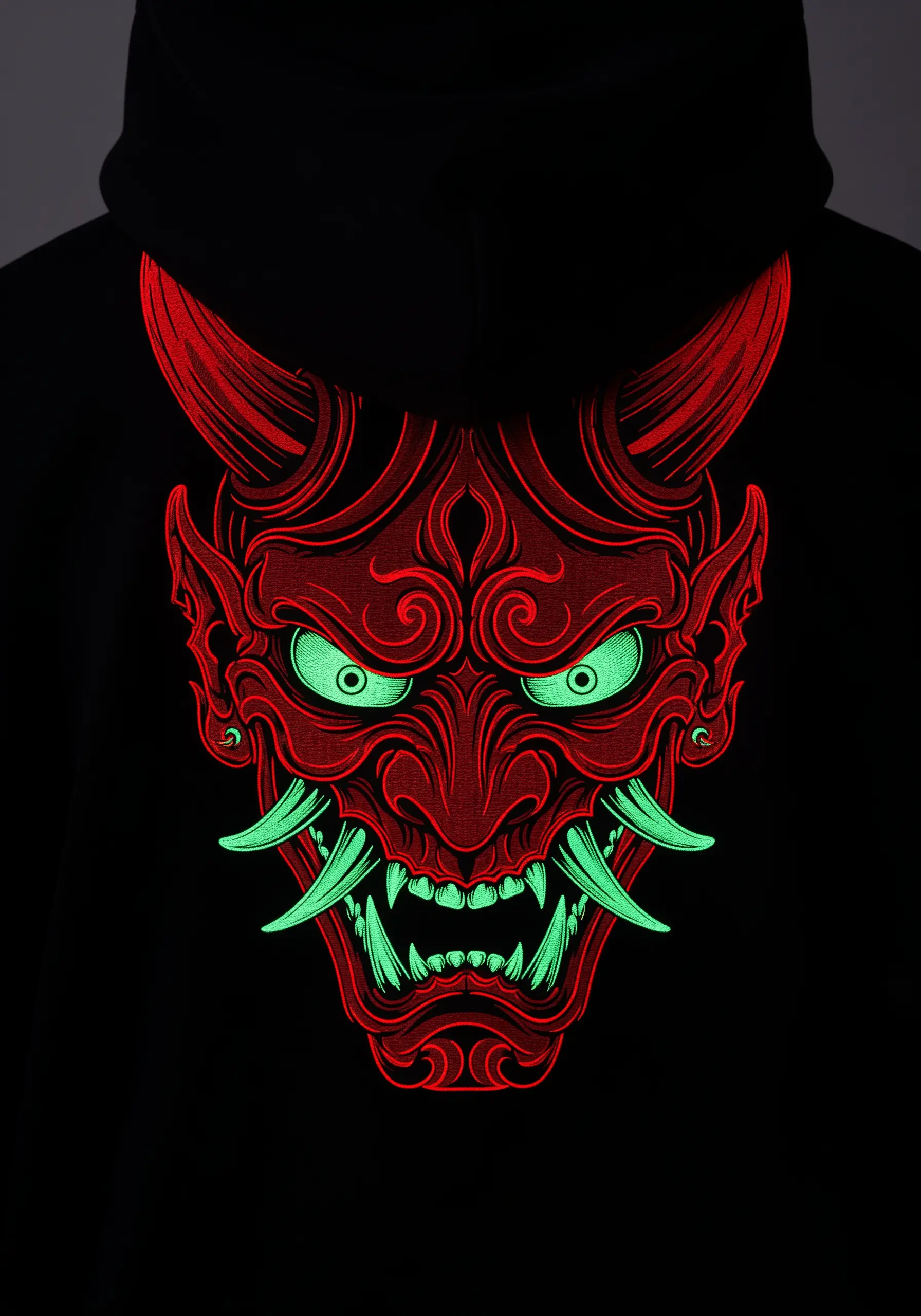 A detailed red Japanese Oni mask with glowing green eyes and teeth on a black hoodie.