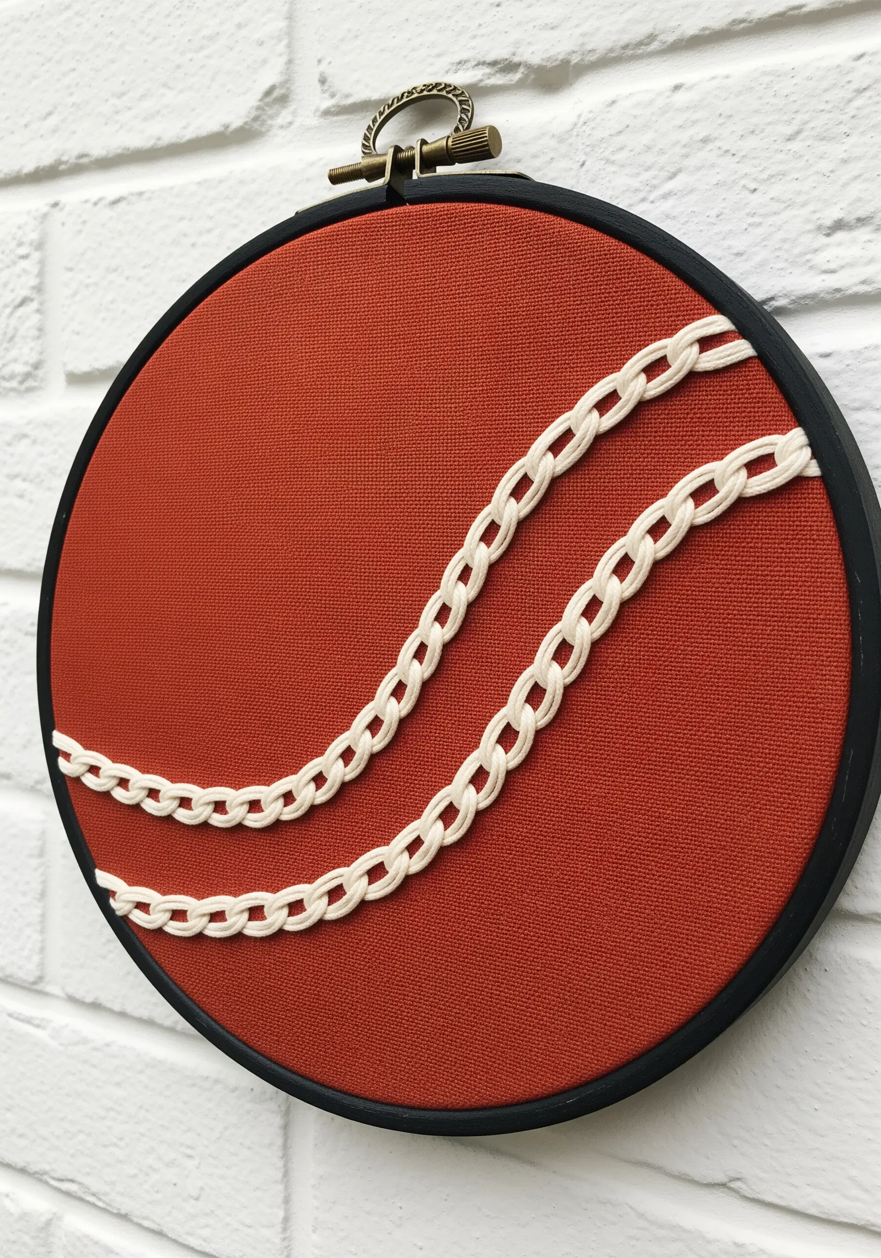 Two parallel lines of white open chain stitch on a rust-colored fabric.