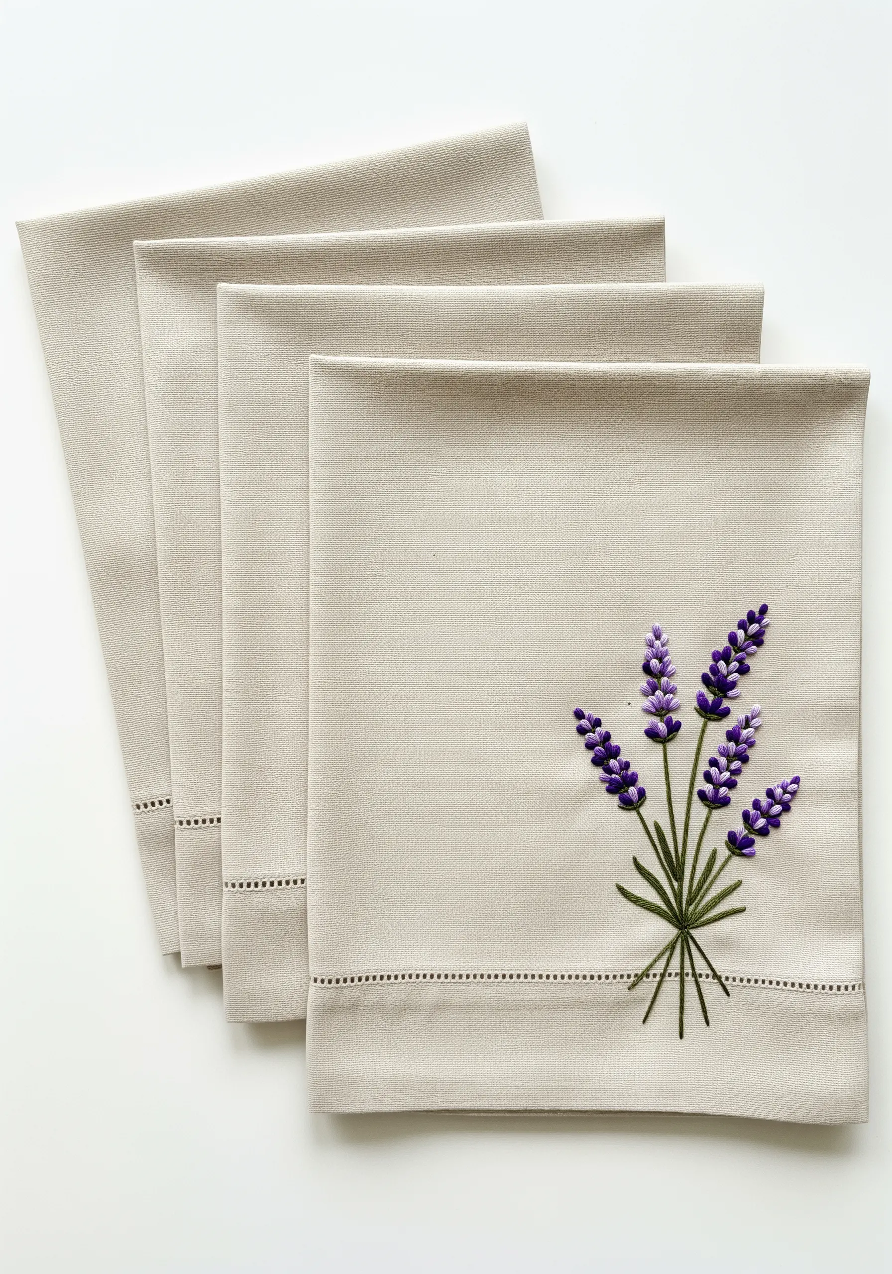 A simple bouquet of lavender embroidered on the corner of a folded beige linen napkin.