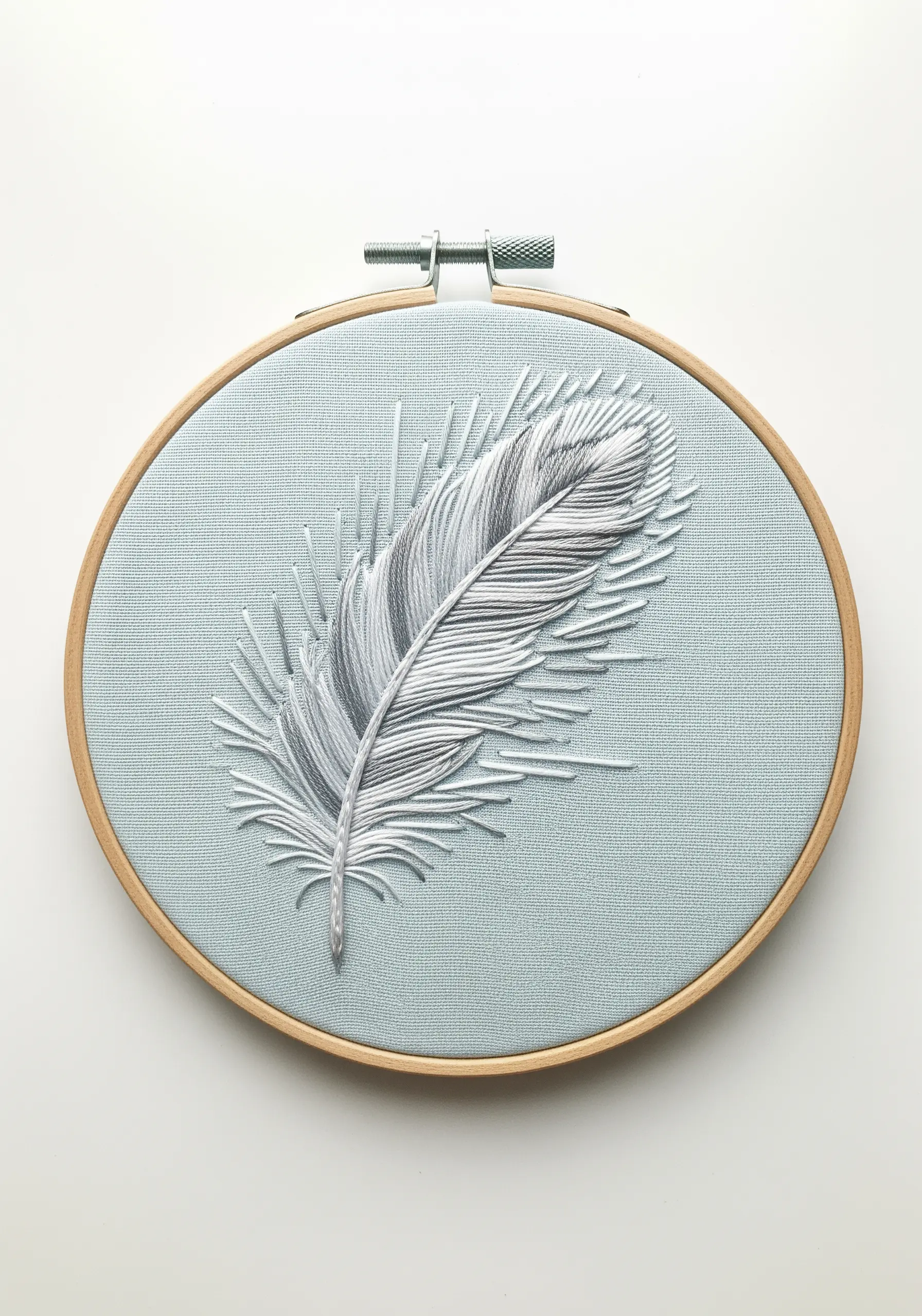 A delicate, realistic feather embroidered with blended white and gray threads.