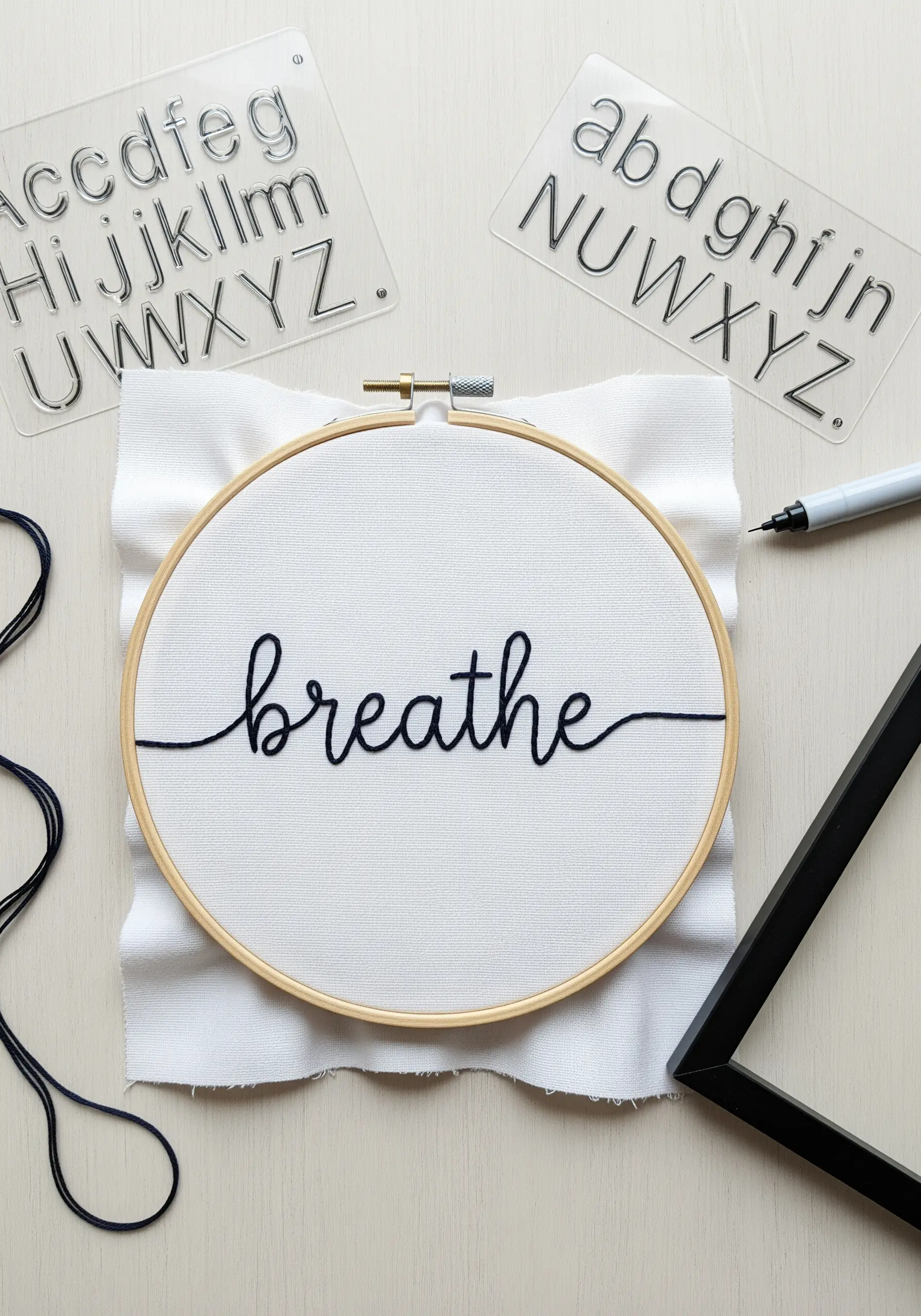 The word 'breathe' embroidered in a clean, cursive script with black thread.