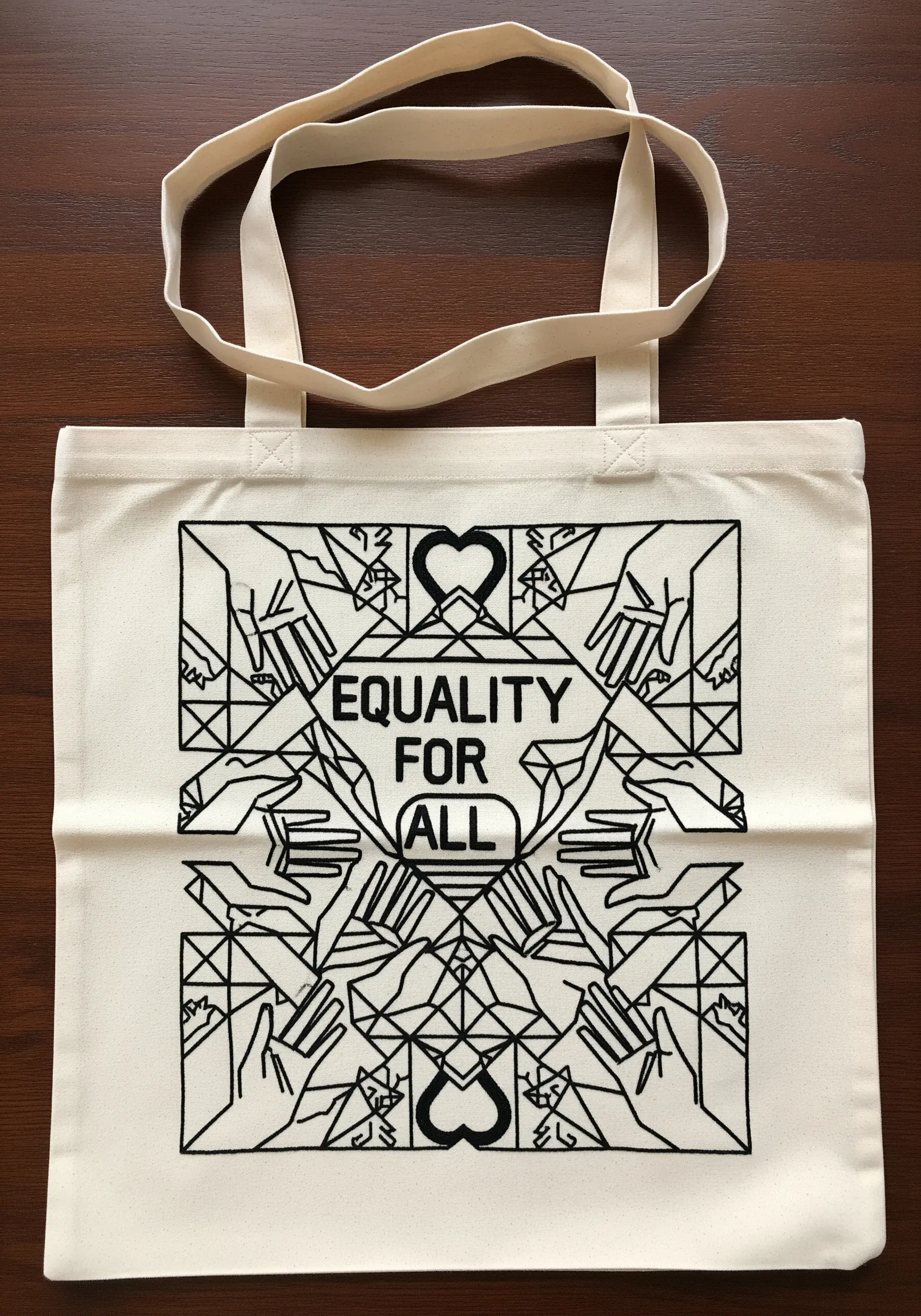Black line art embroidery on a cream tote bag with the words 'Equality For All'.