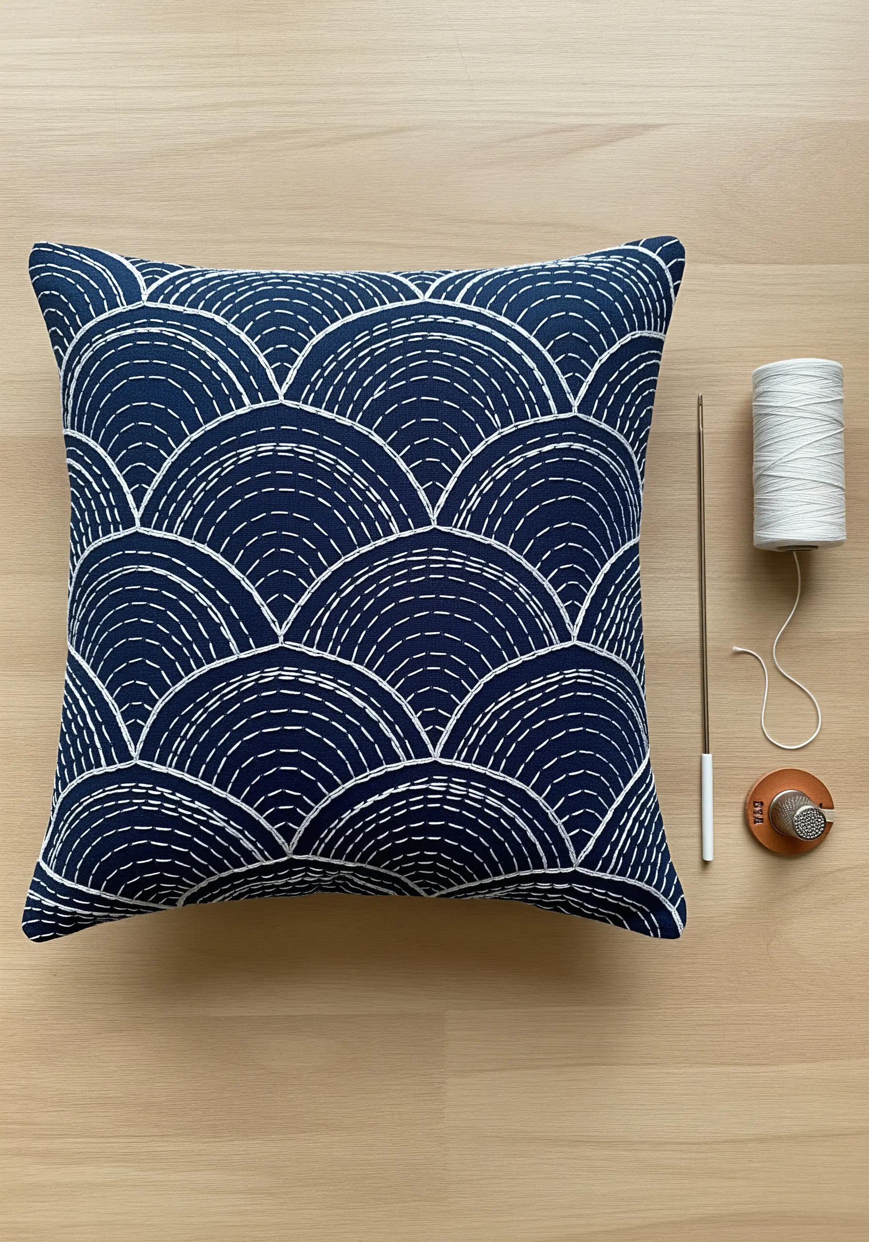 Japanese Sashiko embroidery in a wave pattern with white thread on a navy cushion.