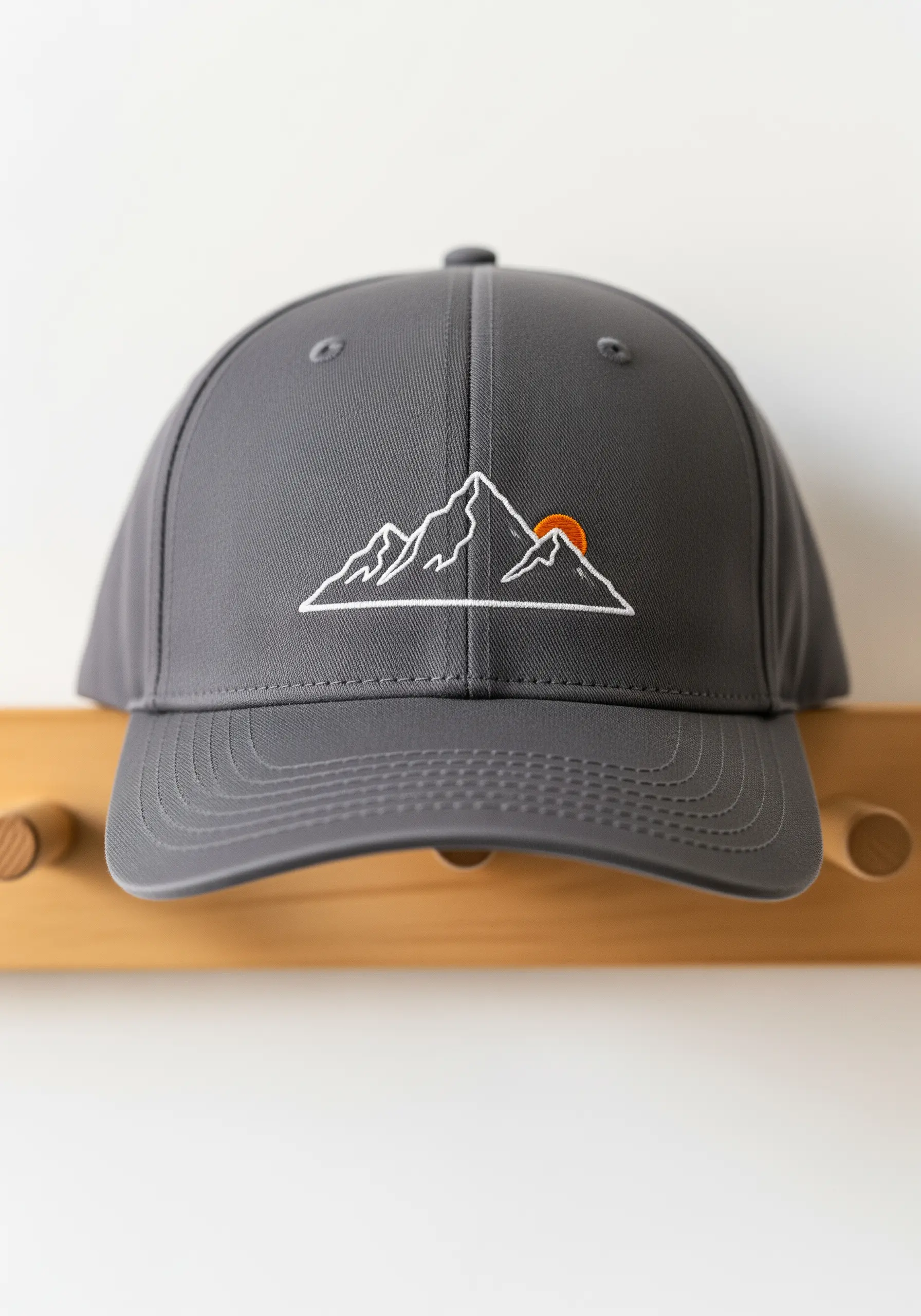A minimalist mountain range outline embroidered in white on the front of a gray baseball cap.