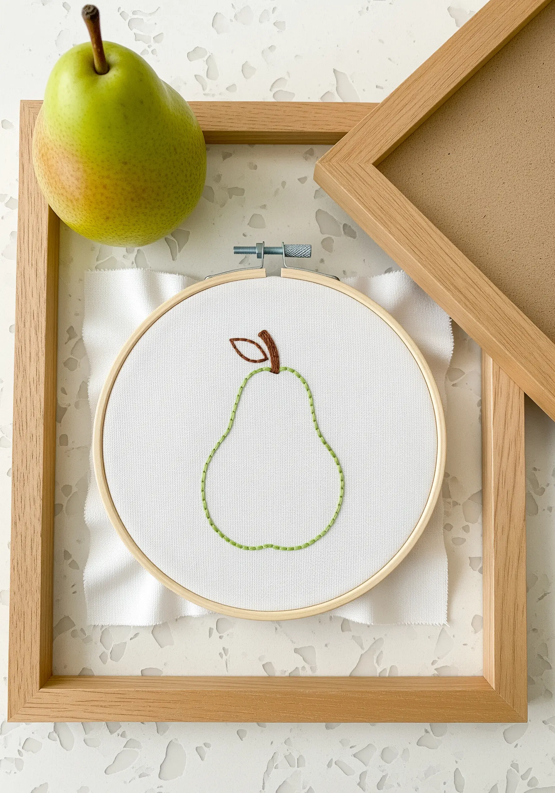 A simple pear outline embroidered with a green running stitch on white fabric.