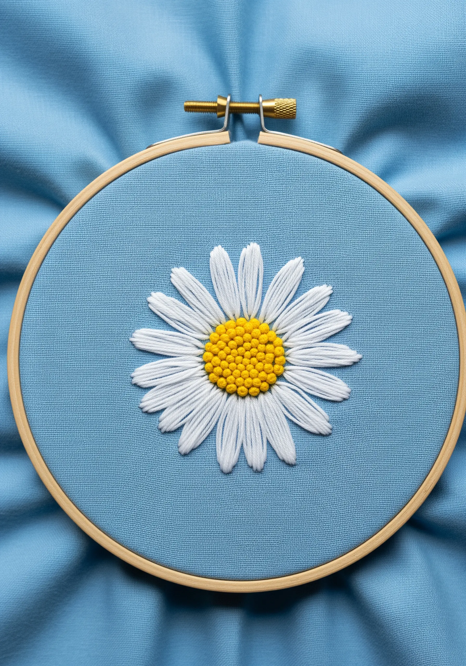 A white daisy with long, looped petals and a dense yellow French knot center.