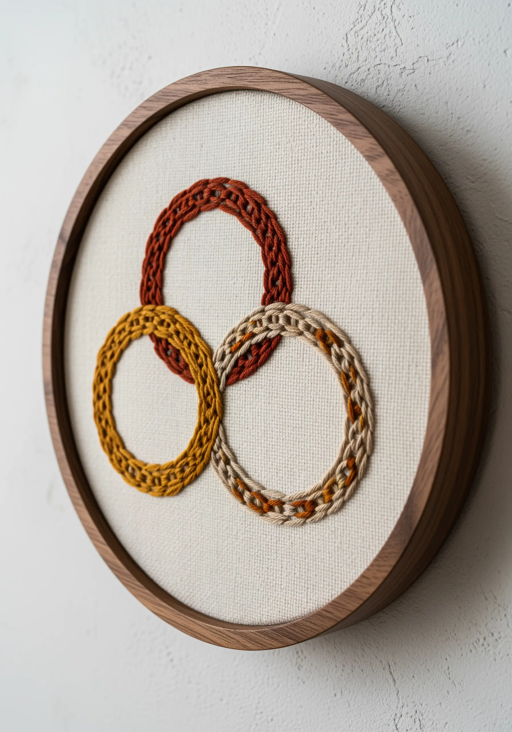 Three interlocking rings in earthy tones with a raised, textured stitch.