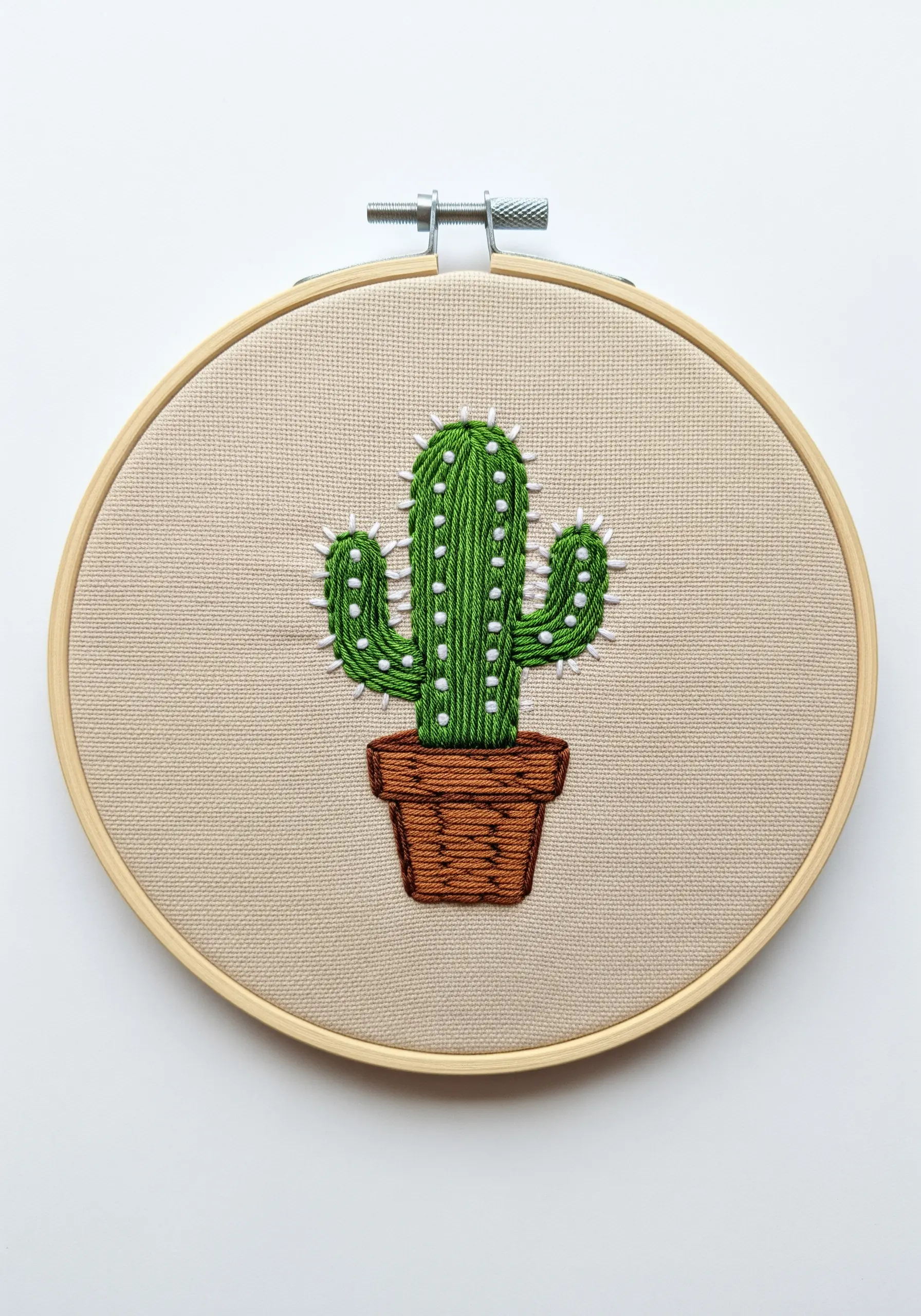 A green satin-stitched cactus with small white French knots for spines.