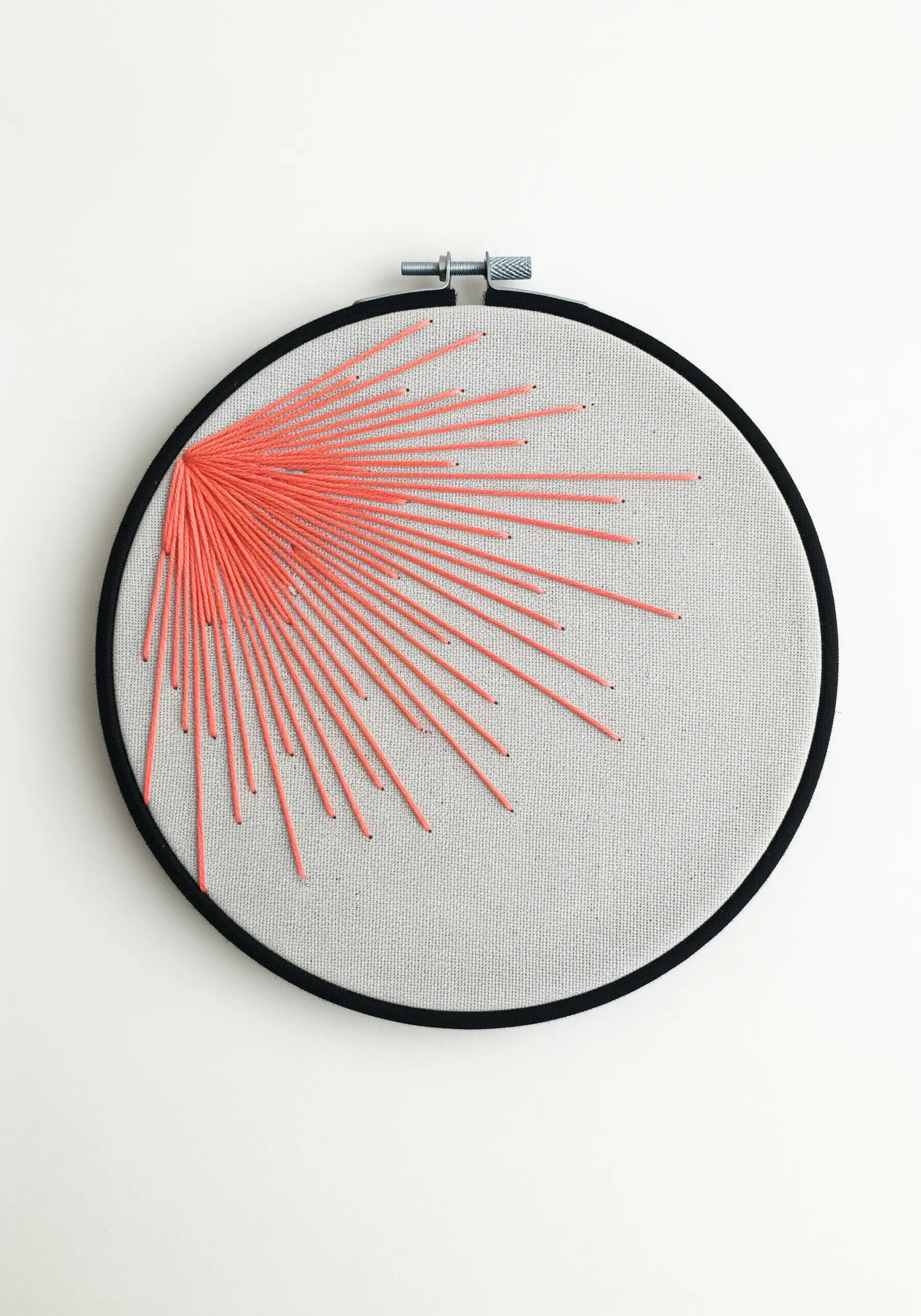 A radiating burst of coral-colored straight stitches on a light gray fabric.