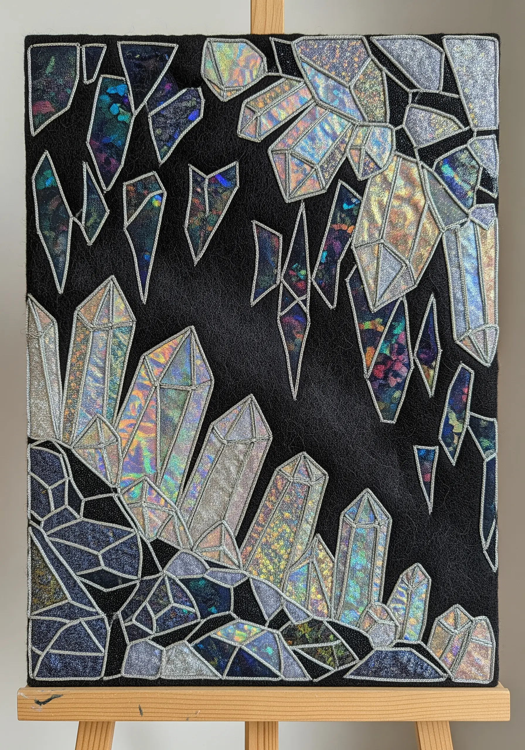 Fabric collage of holographic crystals outlined with silver satin stitch.