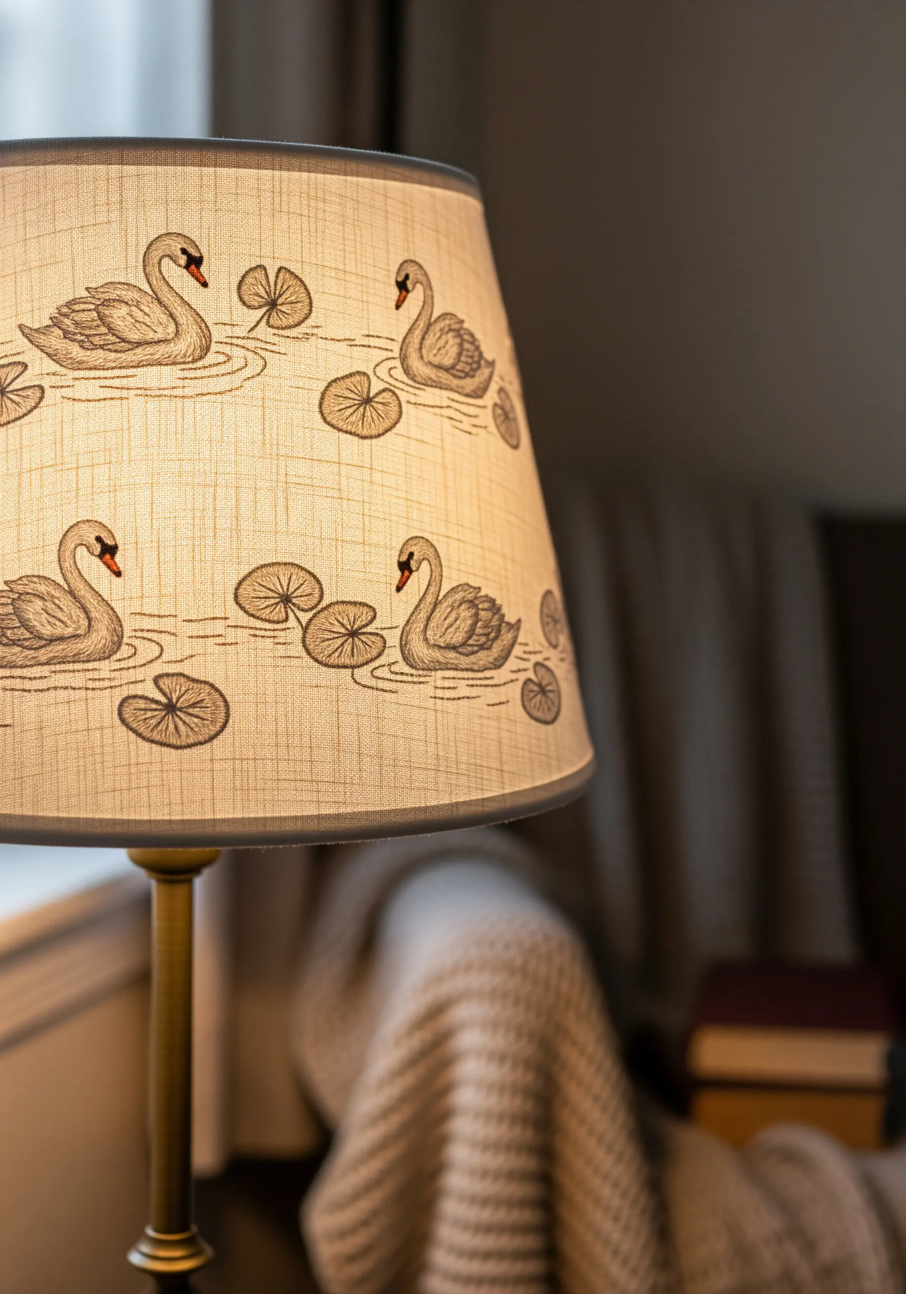 A fabric lampshade decorated with a repeating pattern of simple, line-art swan embroidery.