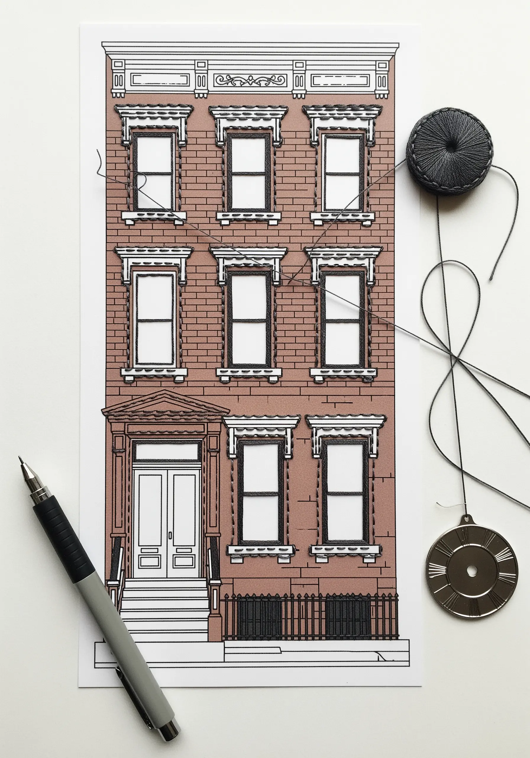 Printed illustration of a building with window details outlined in black thread.