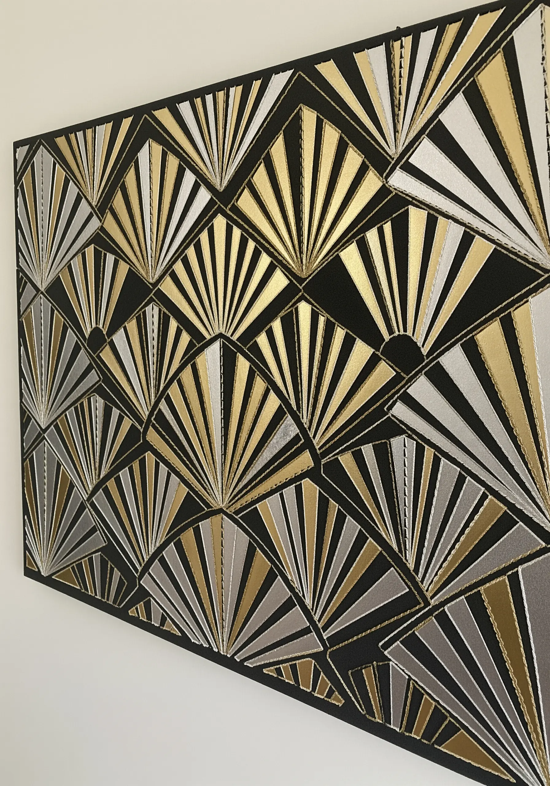 An Art Deco fan pattern created with layered gold and silver paper on a black canvas.