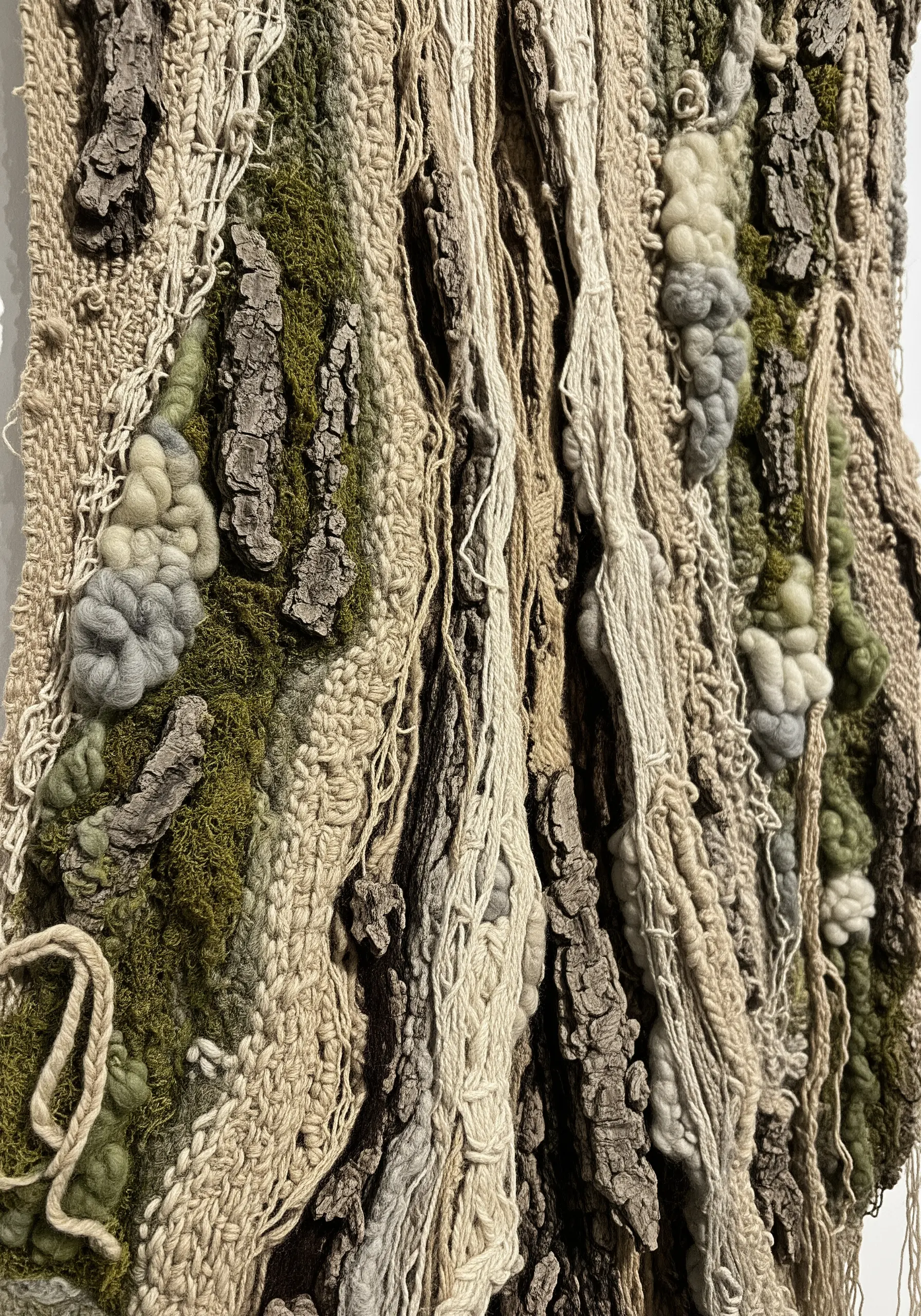 A highly textured textile wall hanging that mimics tree bark using yarn, moss, and actual bark.