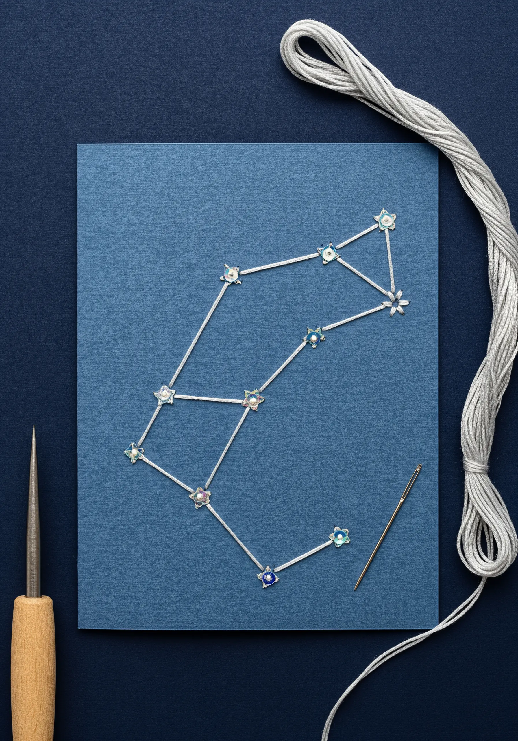 A stitched constellation on blue paper with small, iridescent beads for stars.