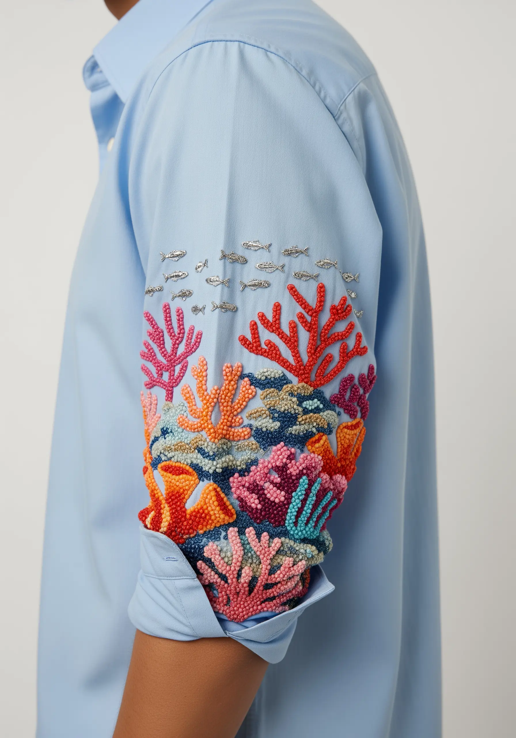 A textured coral reef embroidered on a shirt cuff with French knots, beads, and metallic thread.