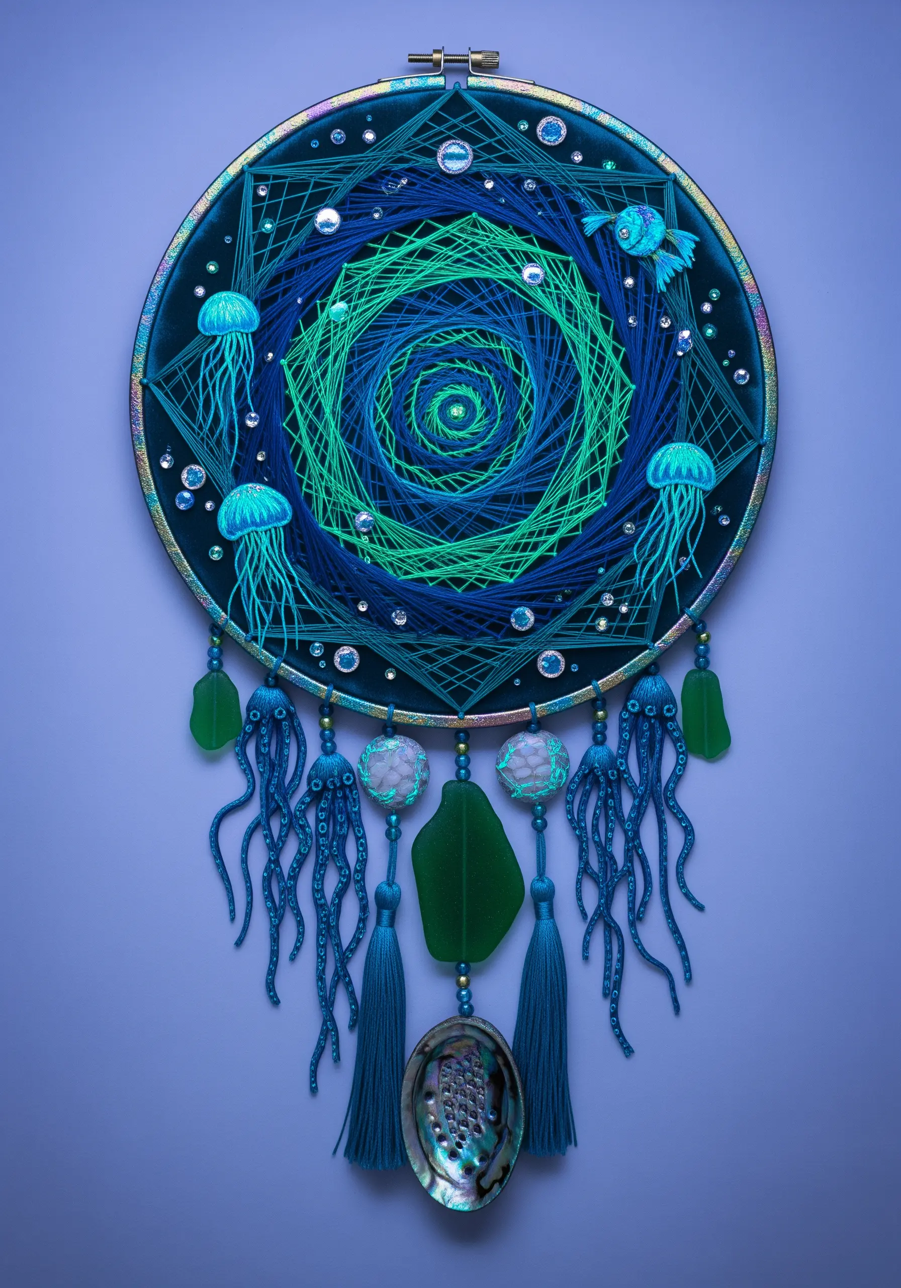 Deep sea dreamcatcher with a blue-green string art vortex and embroidered jellyfish.
