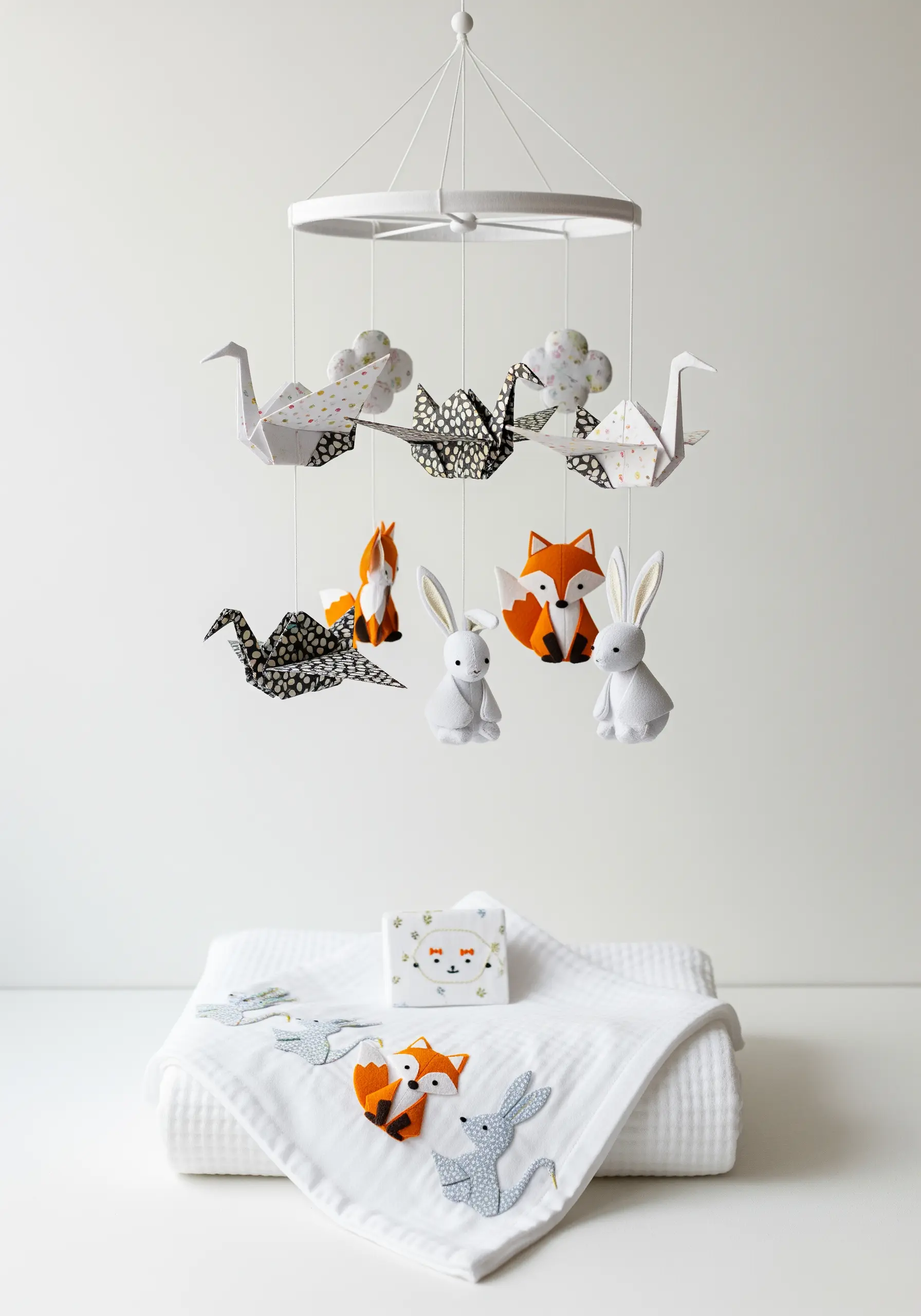 Nursery mobile with embroidered felt animals and patterned origami paper cranes.