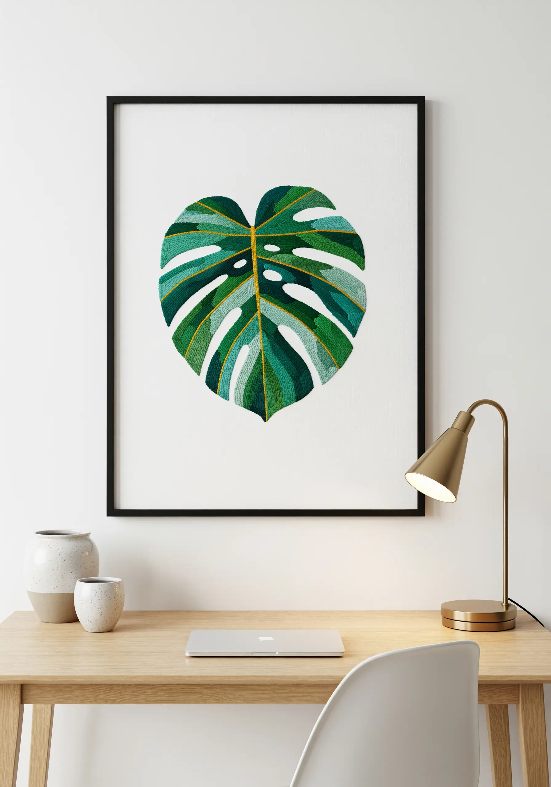 Framed embroidery of a monstera leaf with detailed thread painting in shades of green and gold.