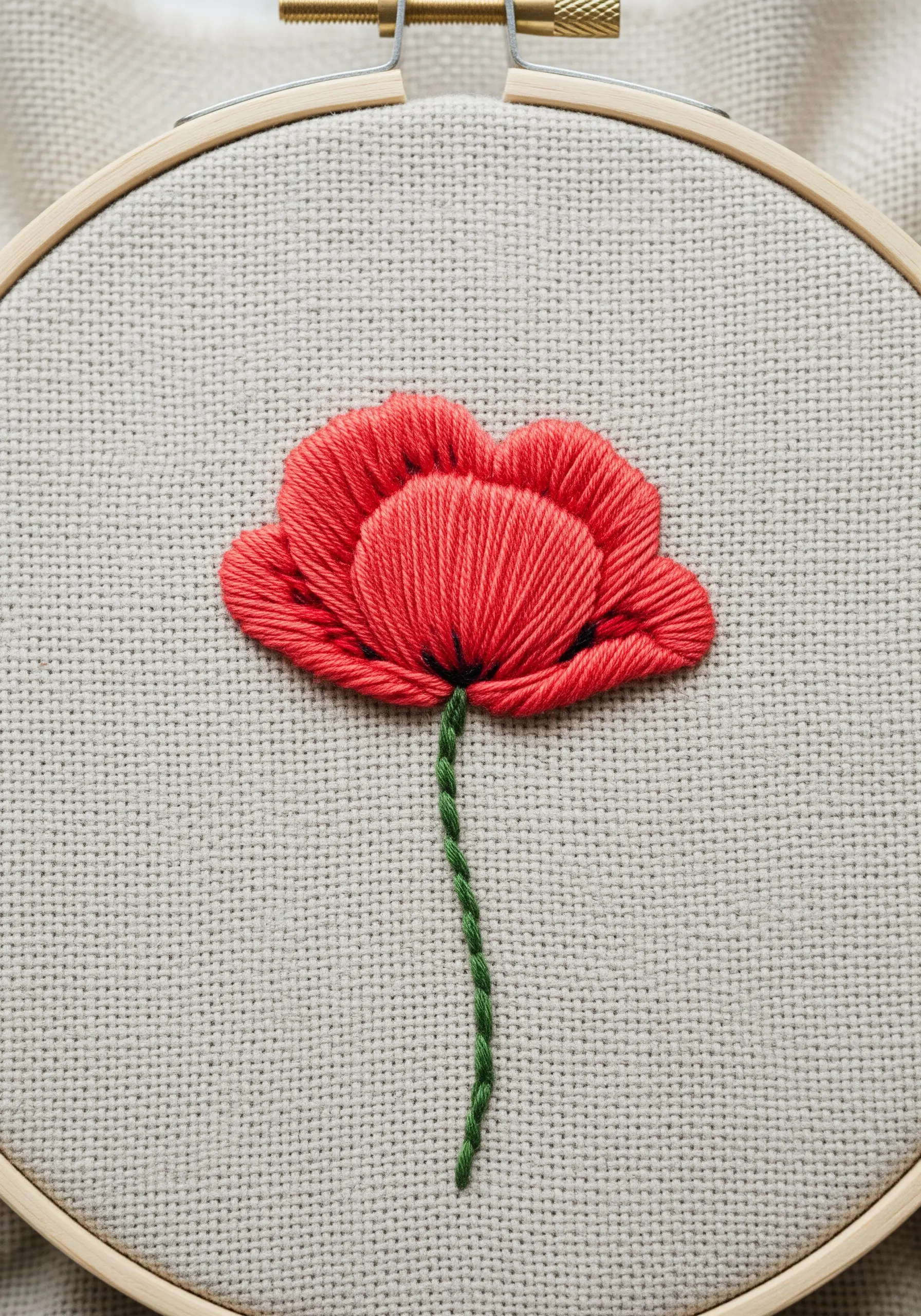 A vibrant red poppy with layered satin stitch petals and a twisted stem.