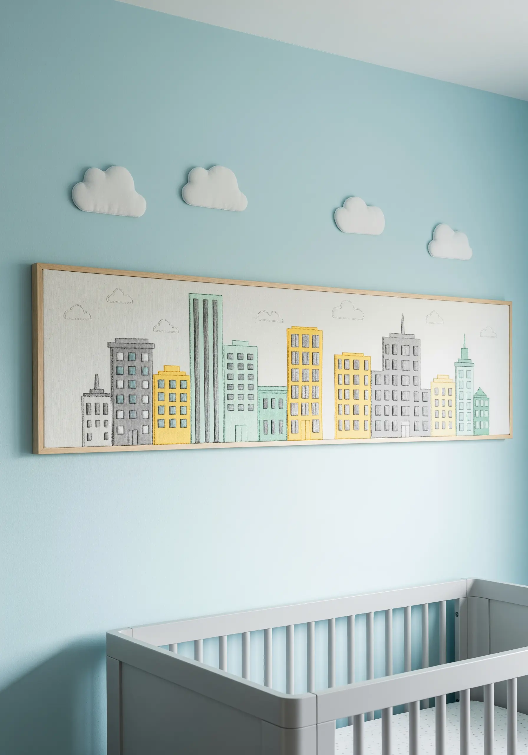 Long rectangular embroidery of a modern city skyline in pastel grays, yellows, and mints.