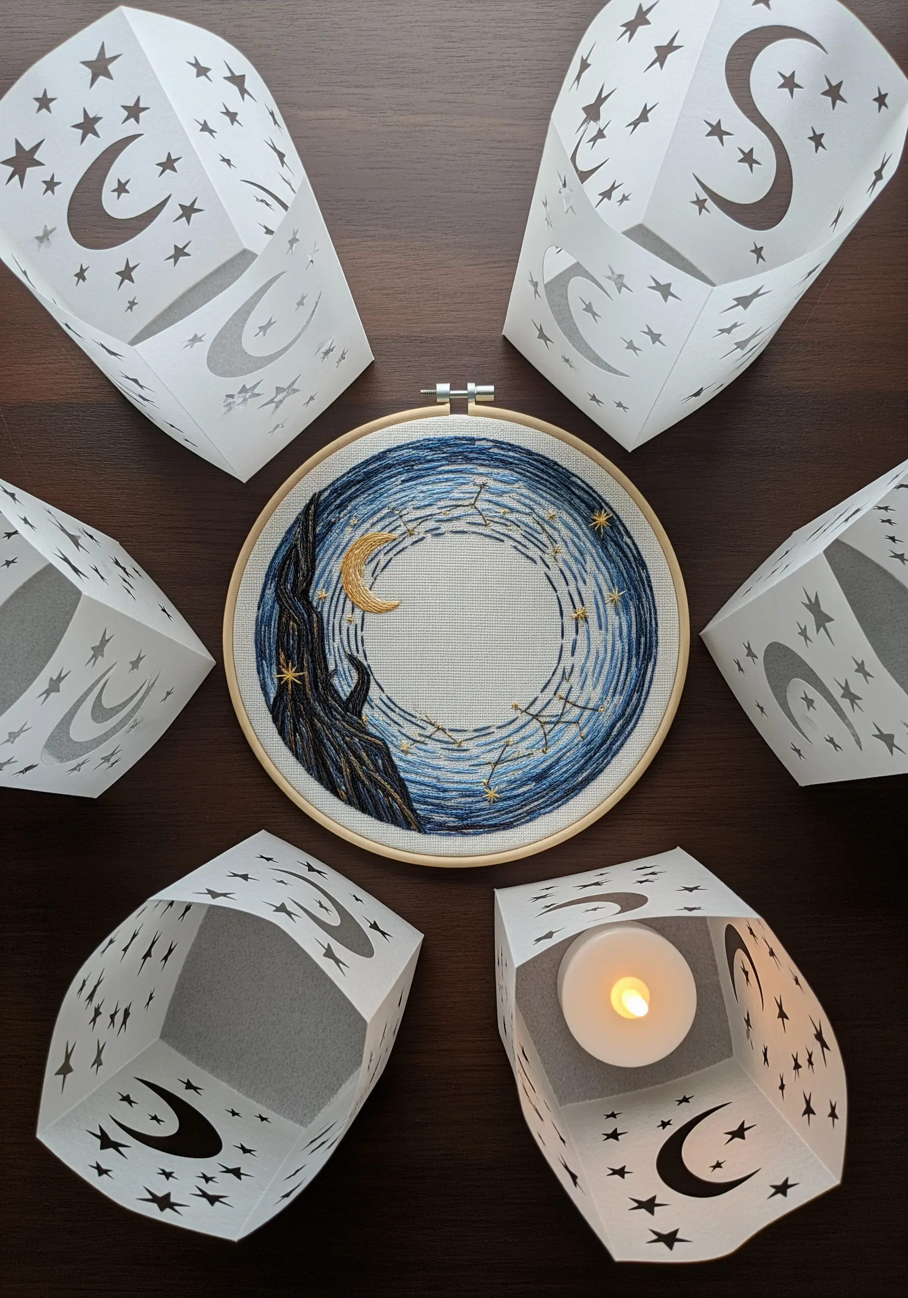 Celestial moon and stars embroidery hoop surrounded by matching paper-cut lanterns.