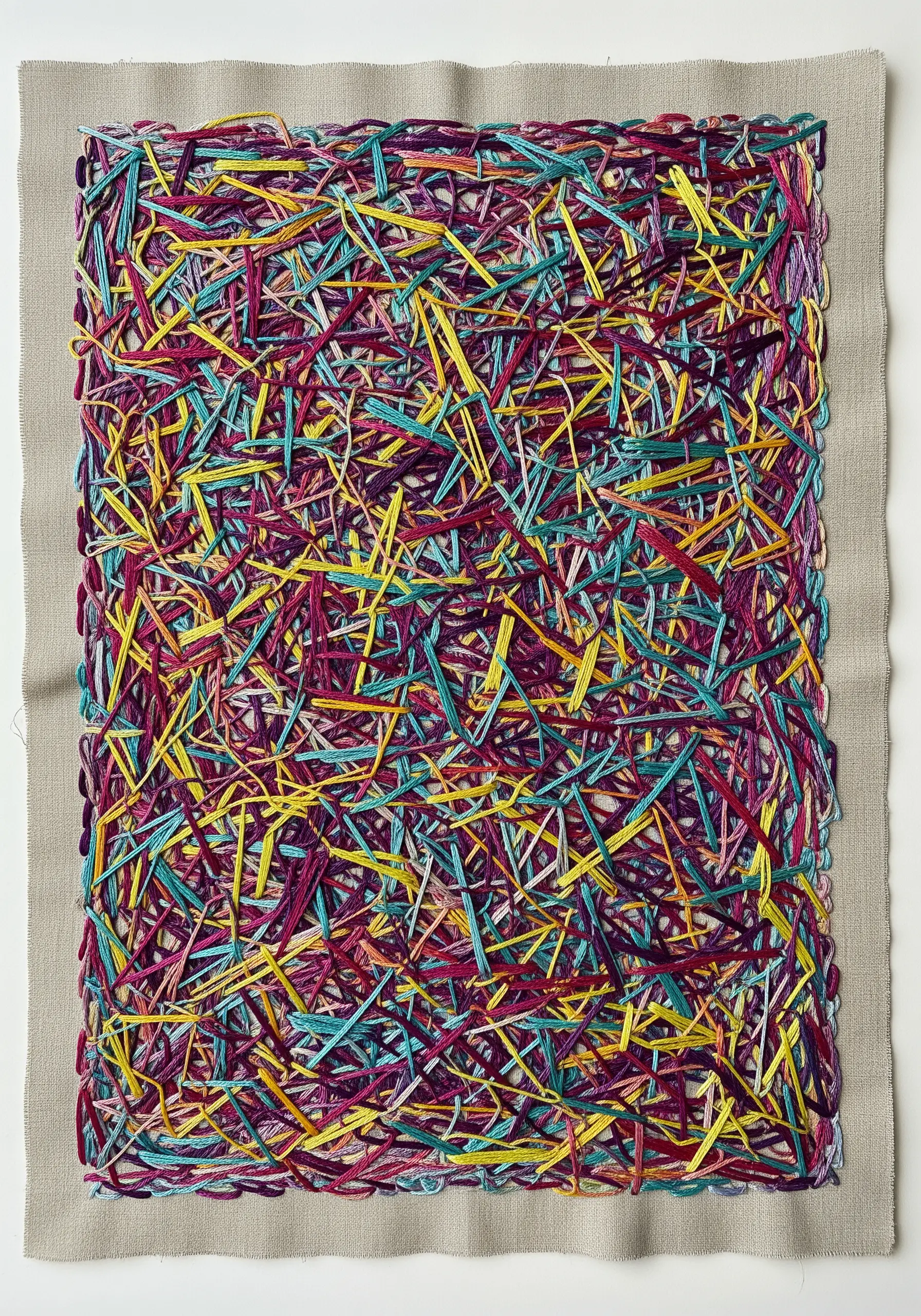 Dense abstract embroidery with interwoven yellow, teal, and magenta threads on a neutral fabric