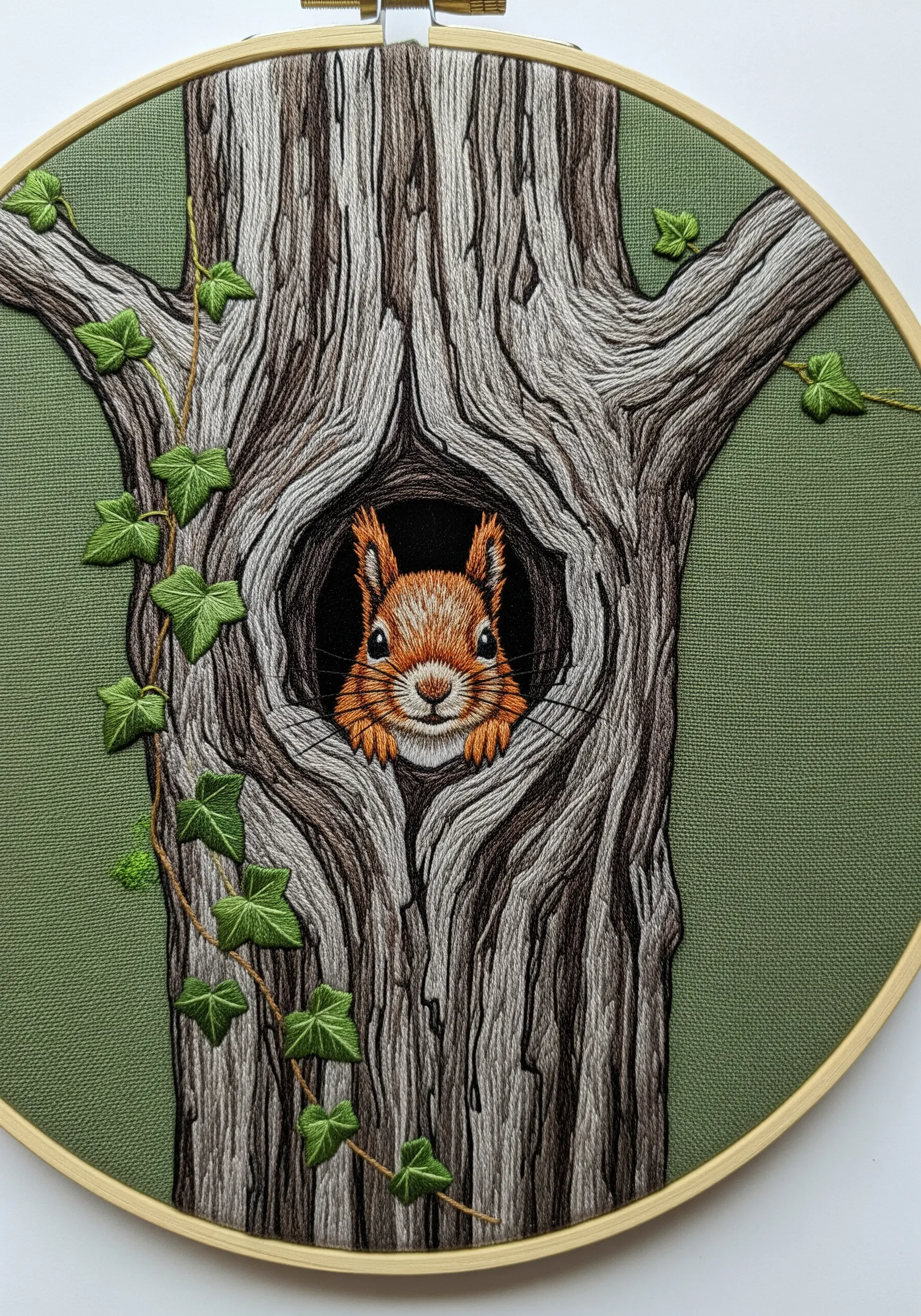 A squirrel peeking out from a hollow in a realistically embroidered tree trunk.