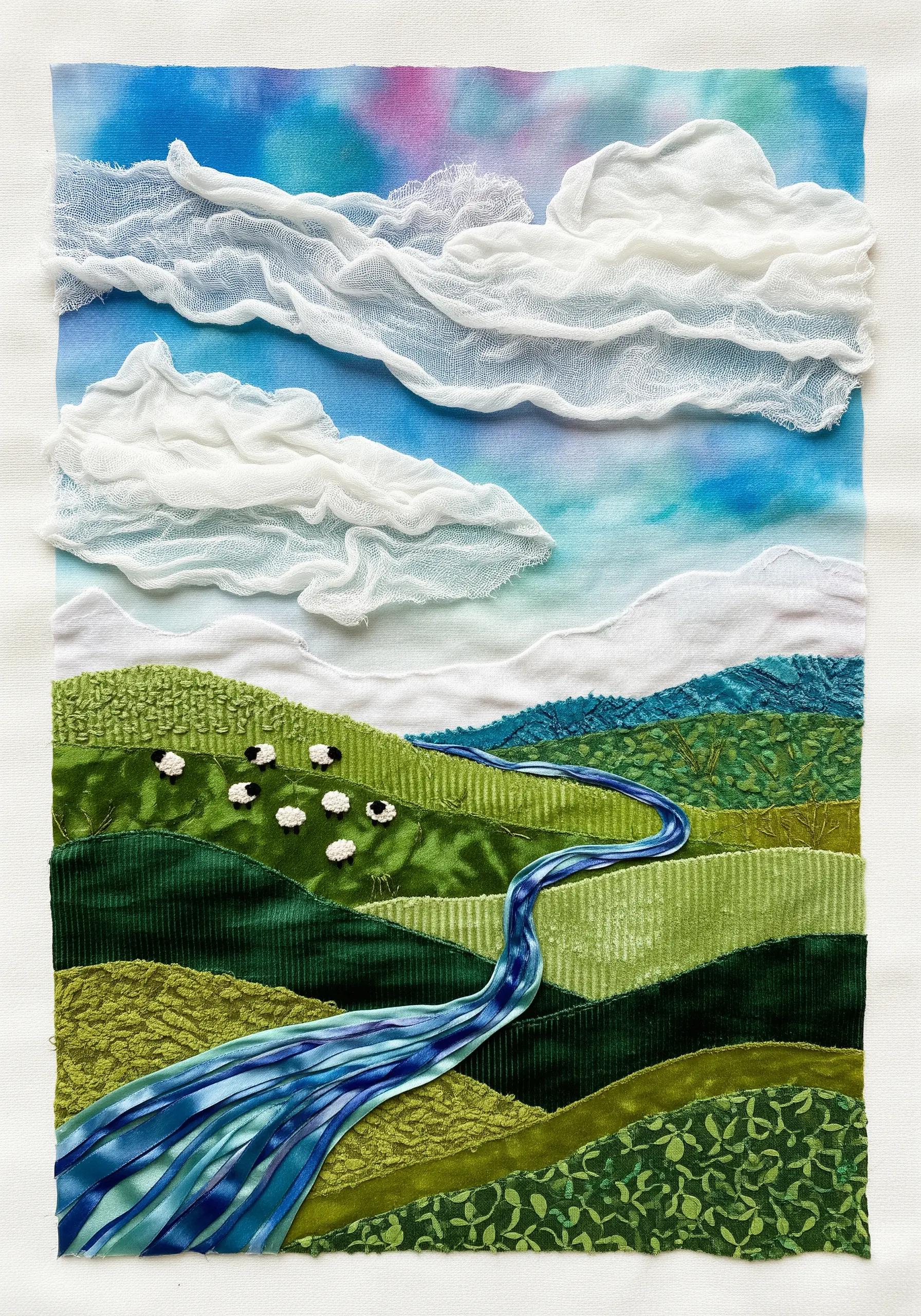 Textile art landscape with rolling green hills made from textured fabrics.