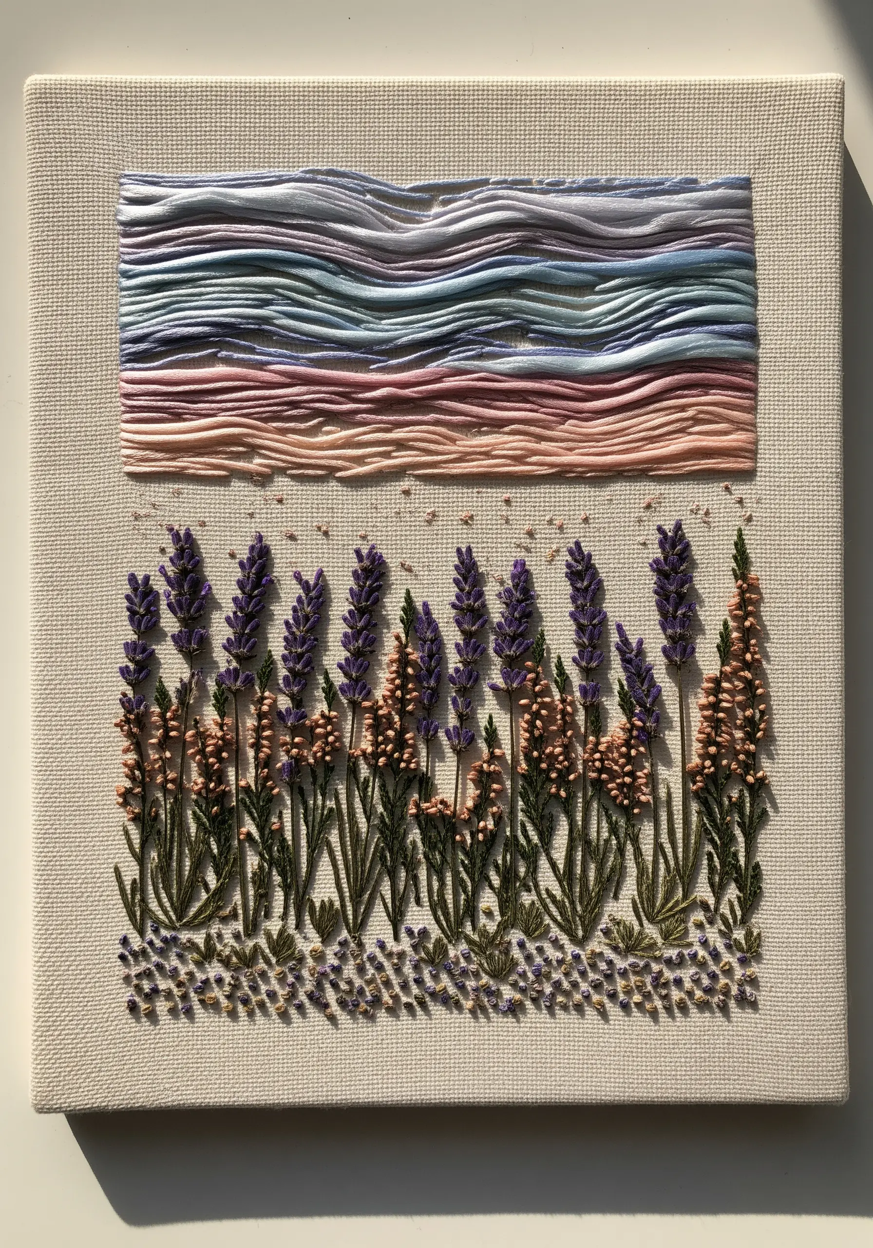 A textured embroidery of a lavender field with a layered, multicolored sky.