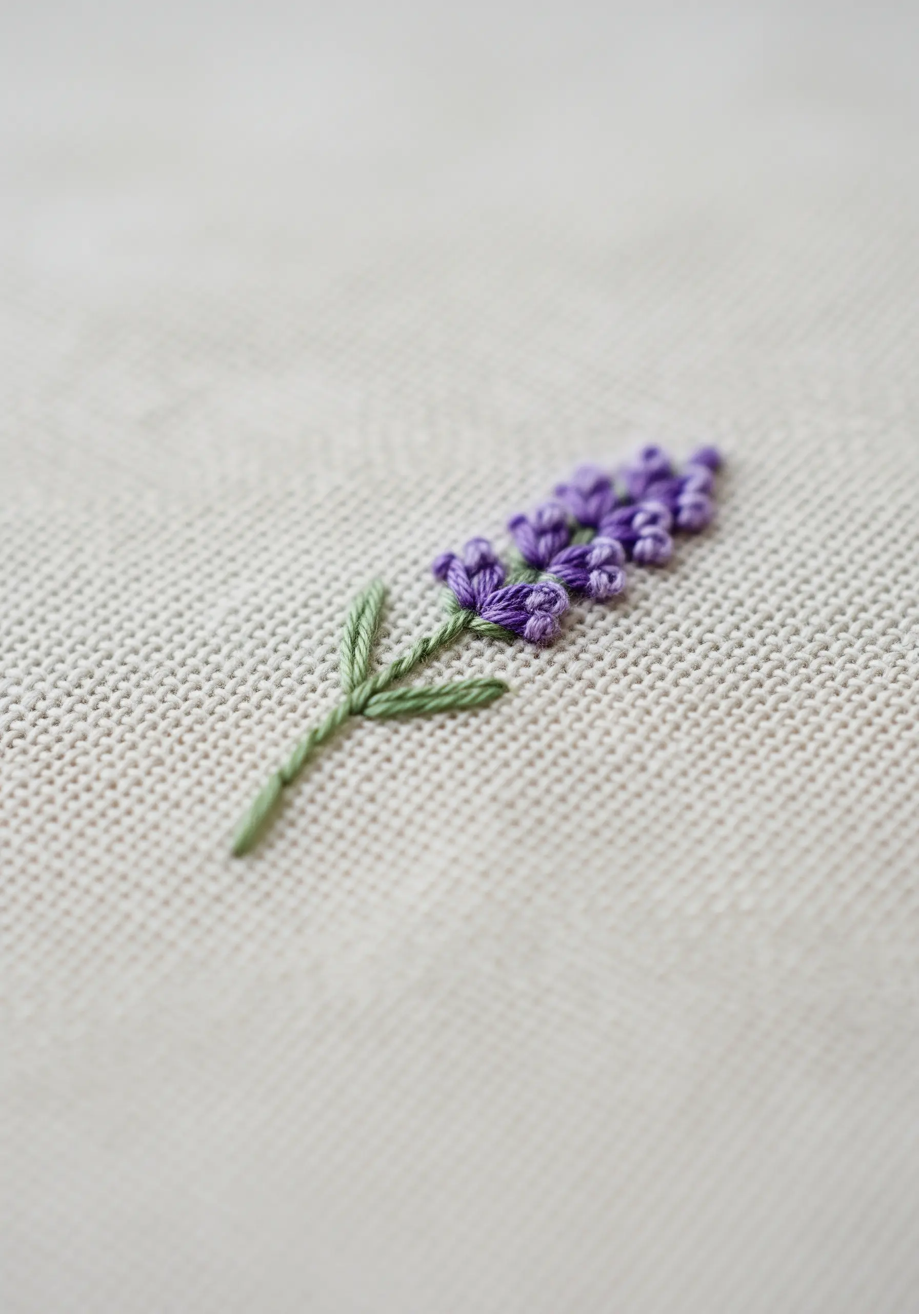 A delicate lavender sprig embroidered with purple French knots and a green stem.