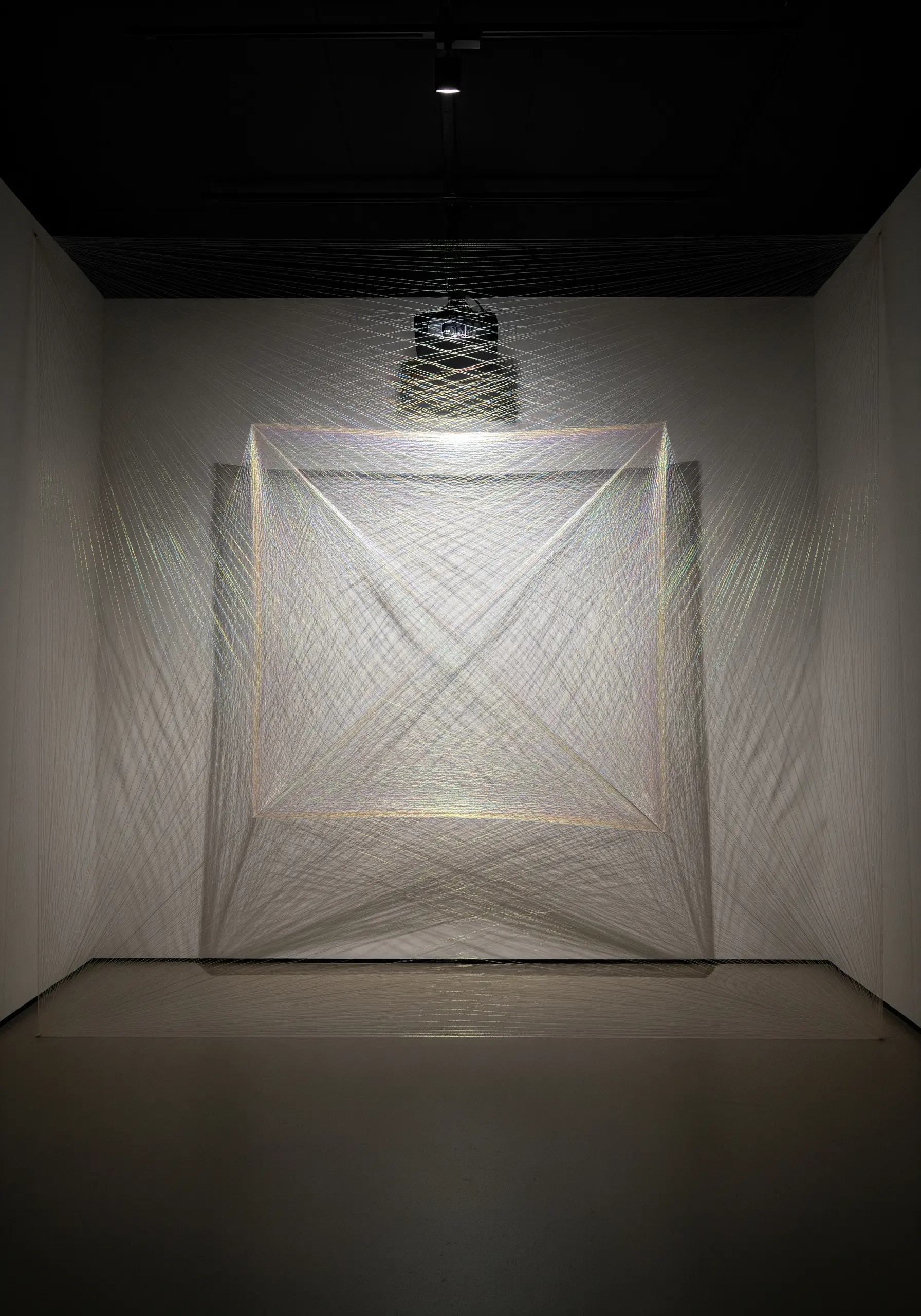 A large, cubic thread installation made with iridescent thread that shimmers with color.
