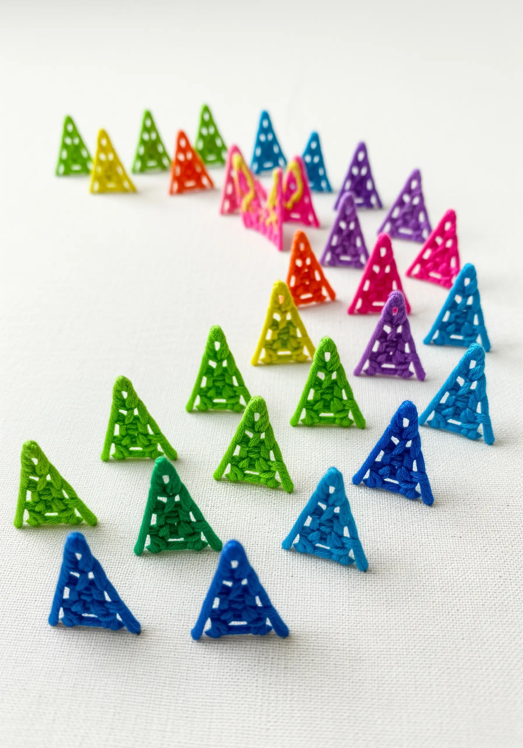 Small, free-standing 3D embroidered triangles in rainbow colors.