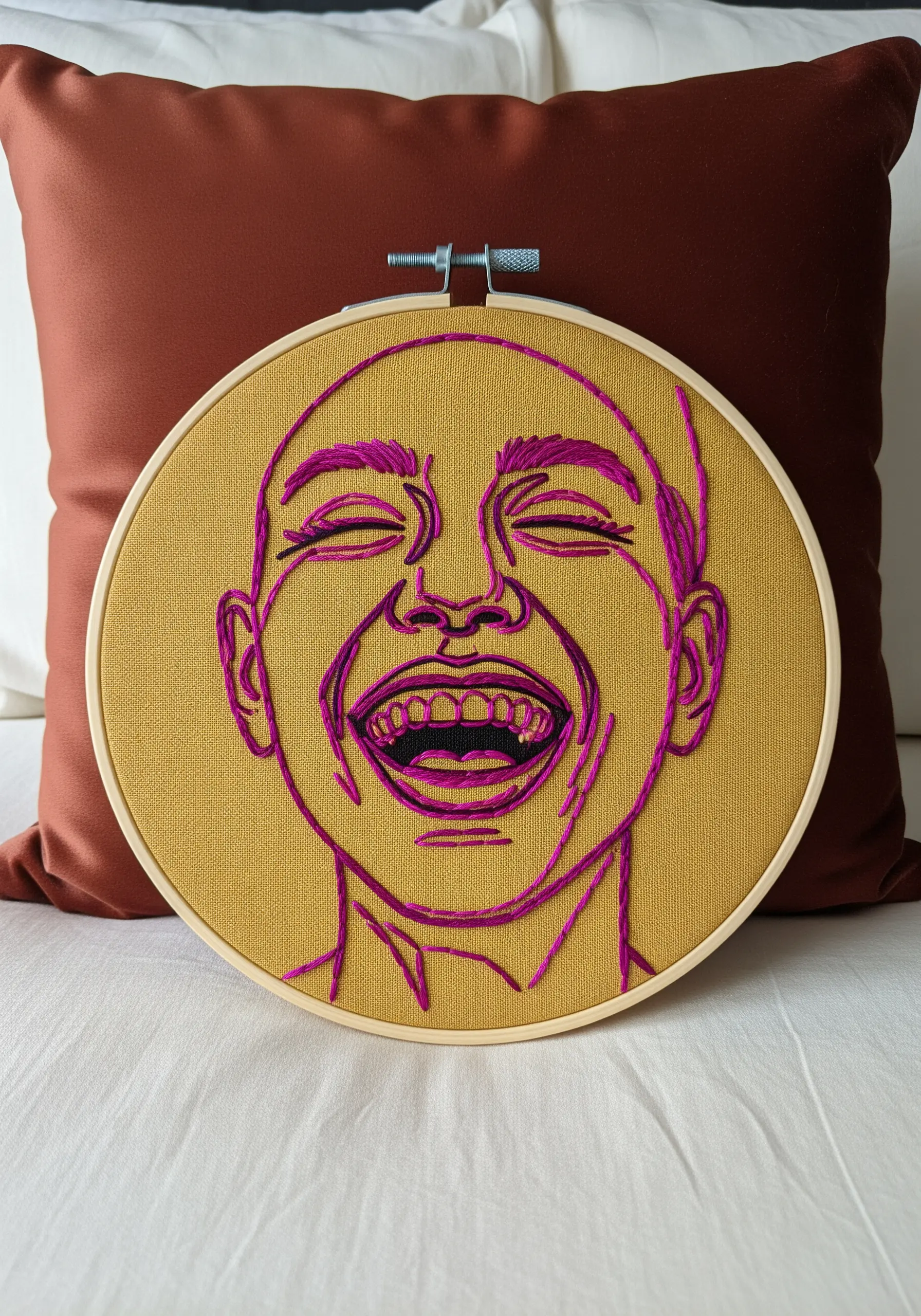 Expressive line art portrait of a laughing person, stitched in vibrant fuchsia on ochre fabric.