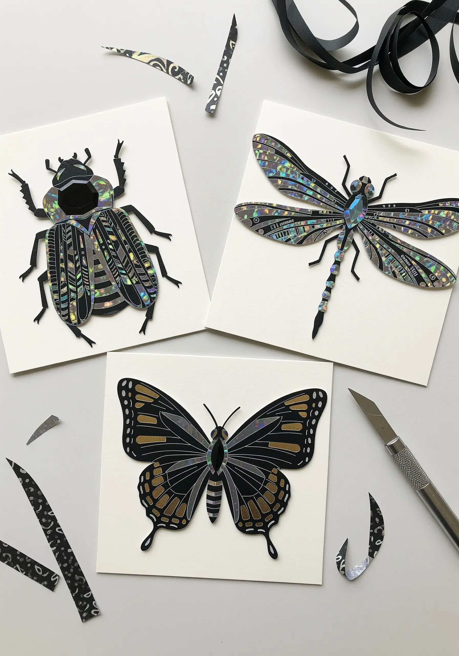 Paper collage of a beetle, dragonfly, and butterfly using iridescent and black paper.