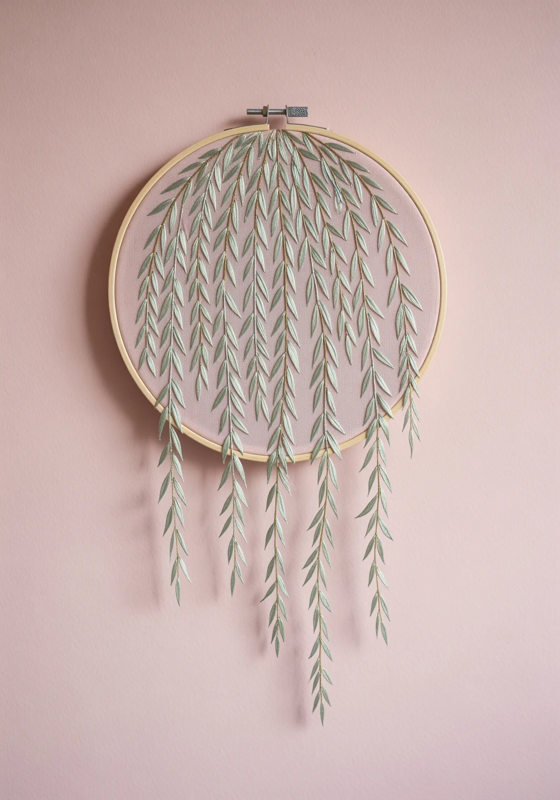 Weeping willow embroidery with threads hanging down past the hoop's edge.