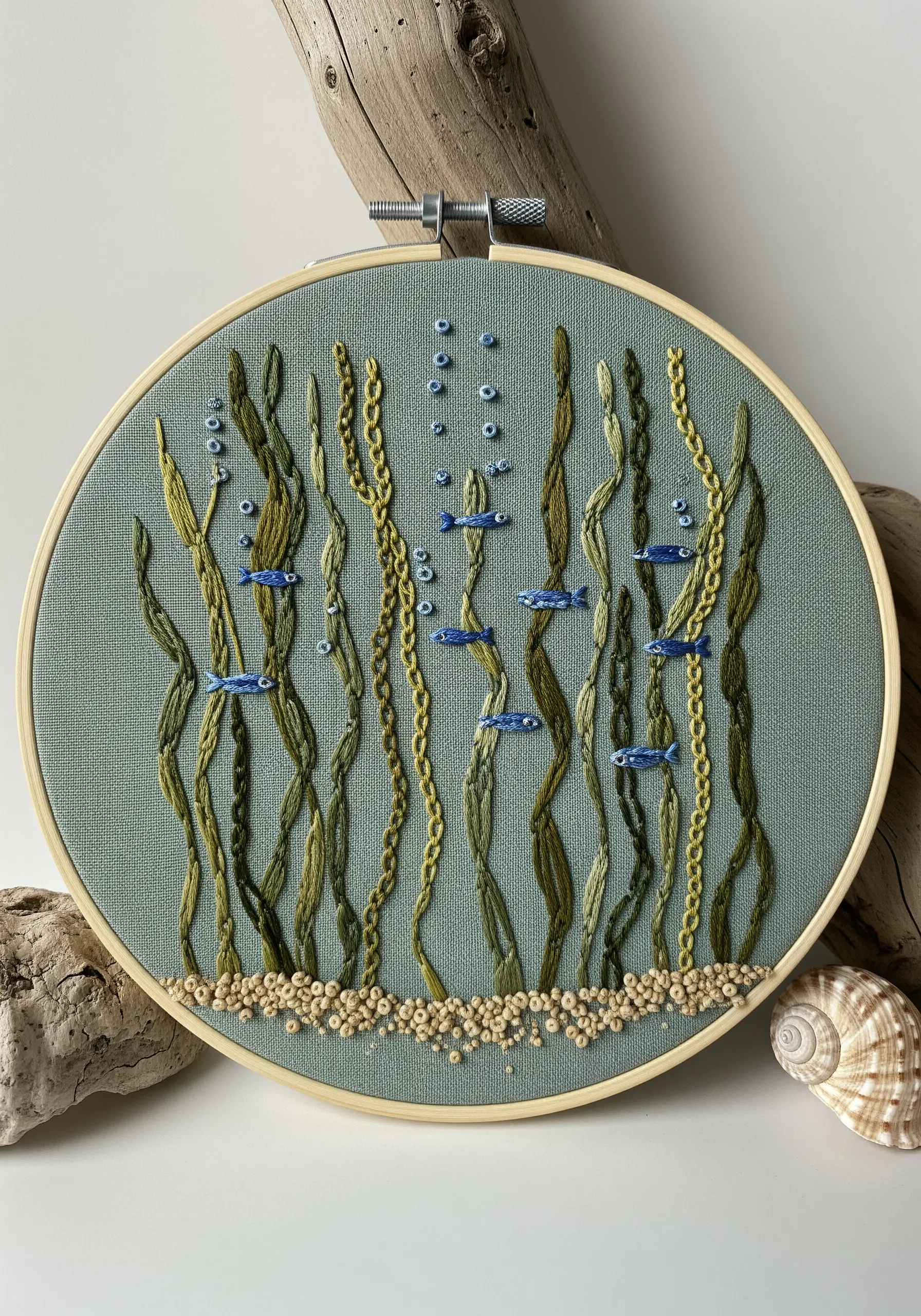 Embroidered underwater scene with green seaweed, blue fish, and French knot bubbles.