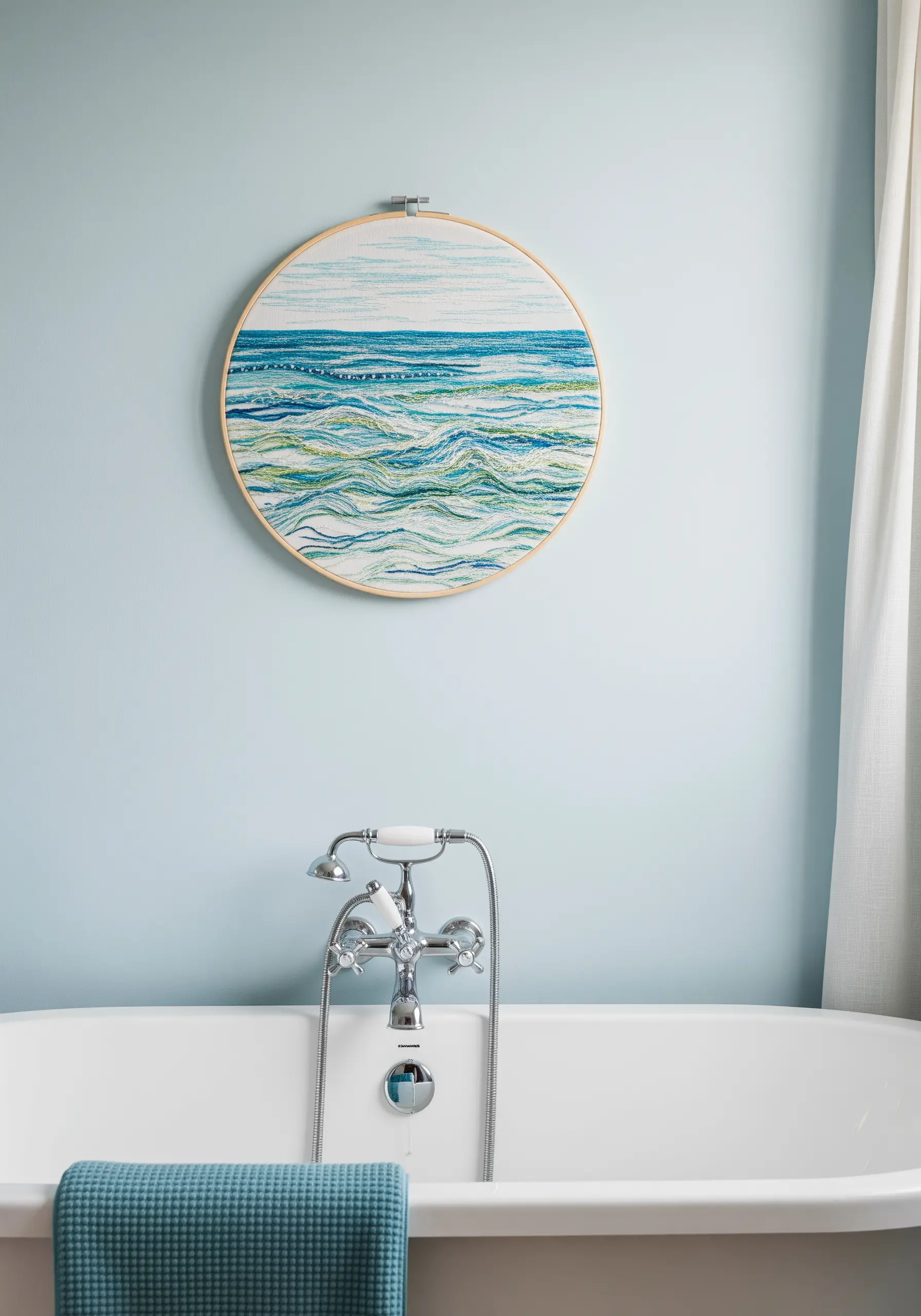 An embroidery hoop showing abstract ocean waves in shades of blue, green, and white.