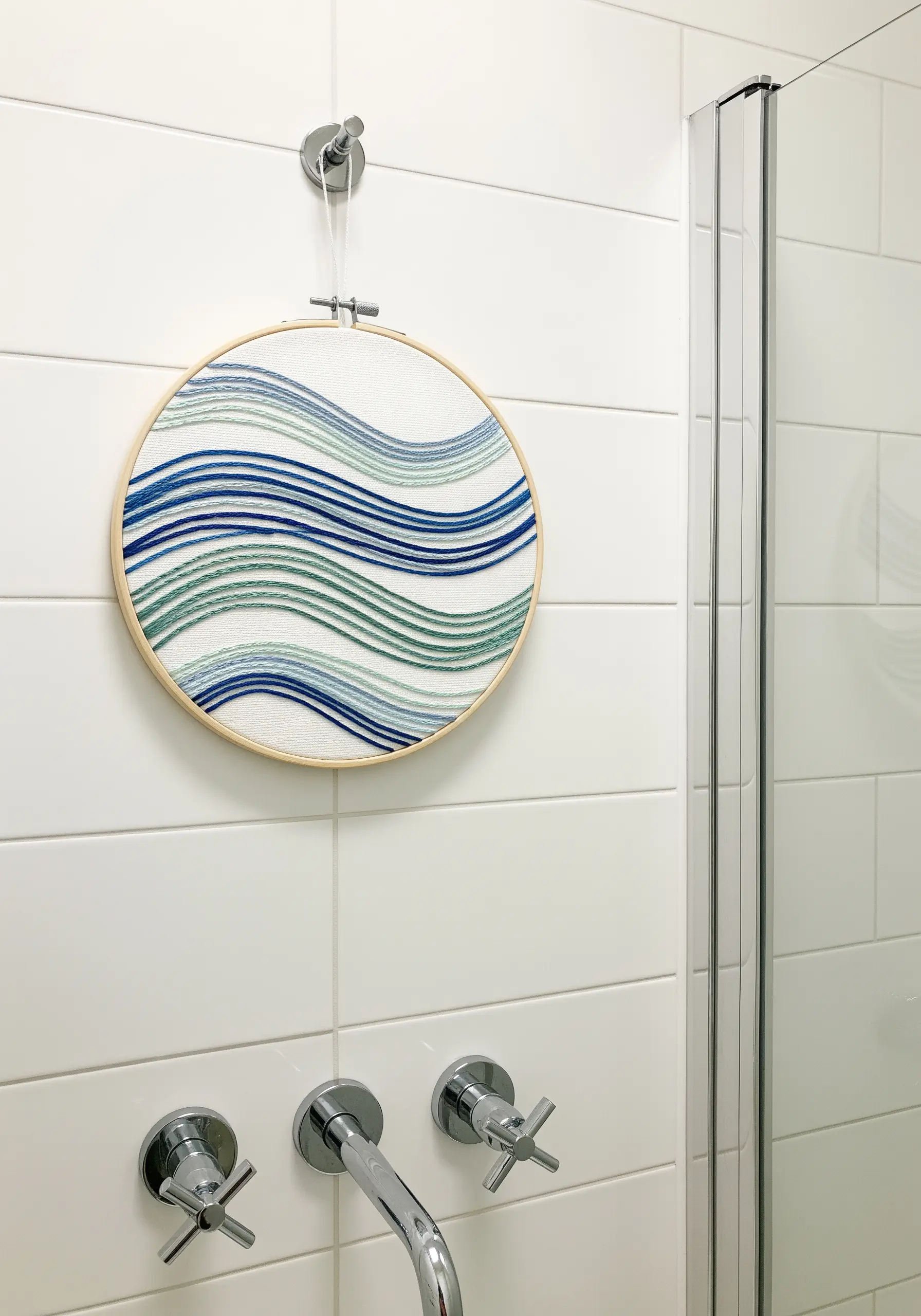 Abstract ocean waves embroidered with layered blue and green threads.