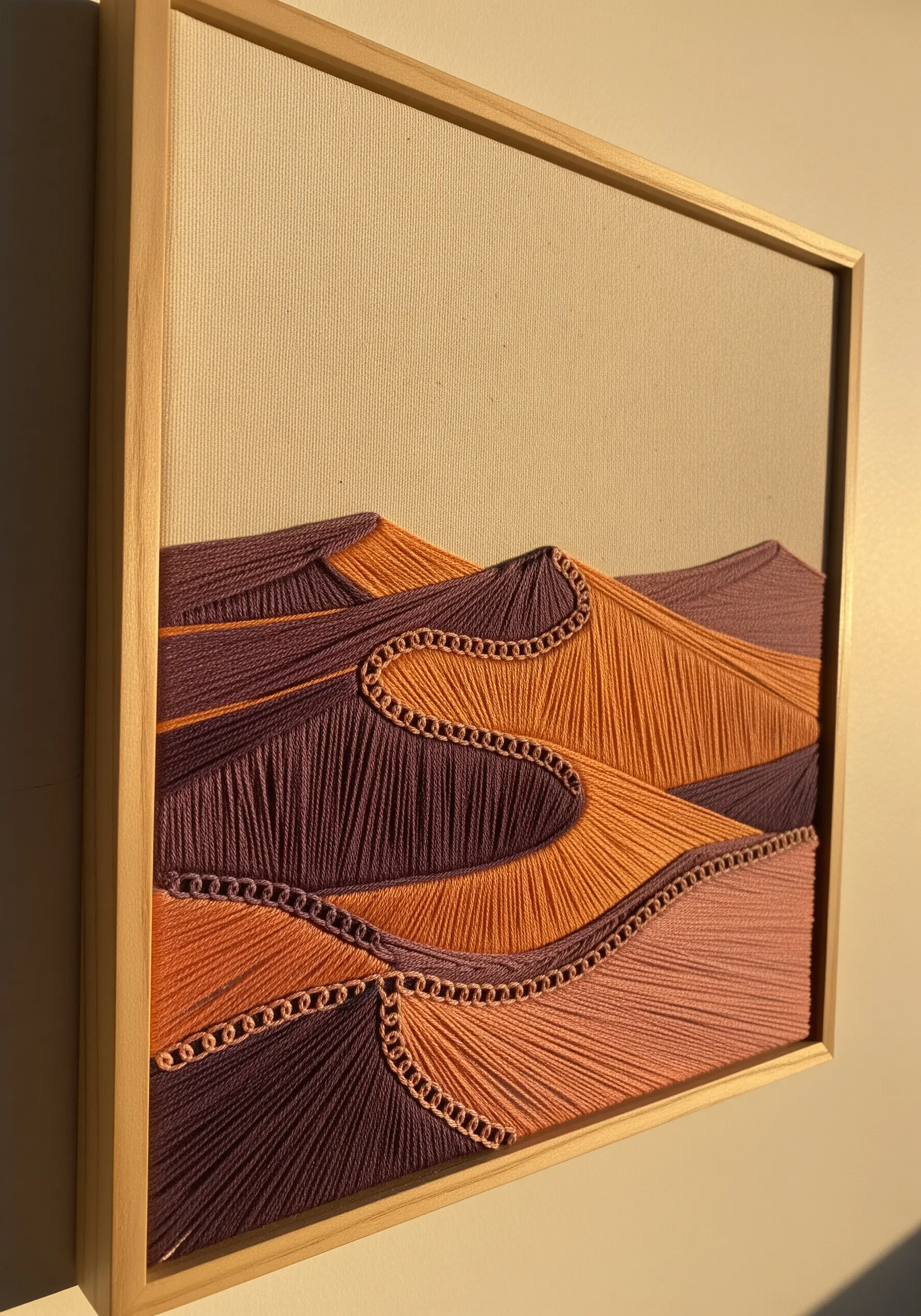 Framed string art of desert dunes in purple and orange, with chain stitch defining the ridges.