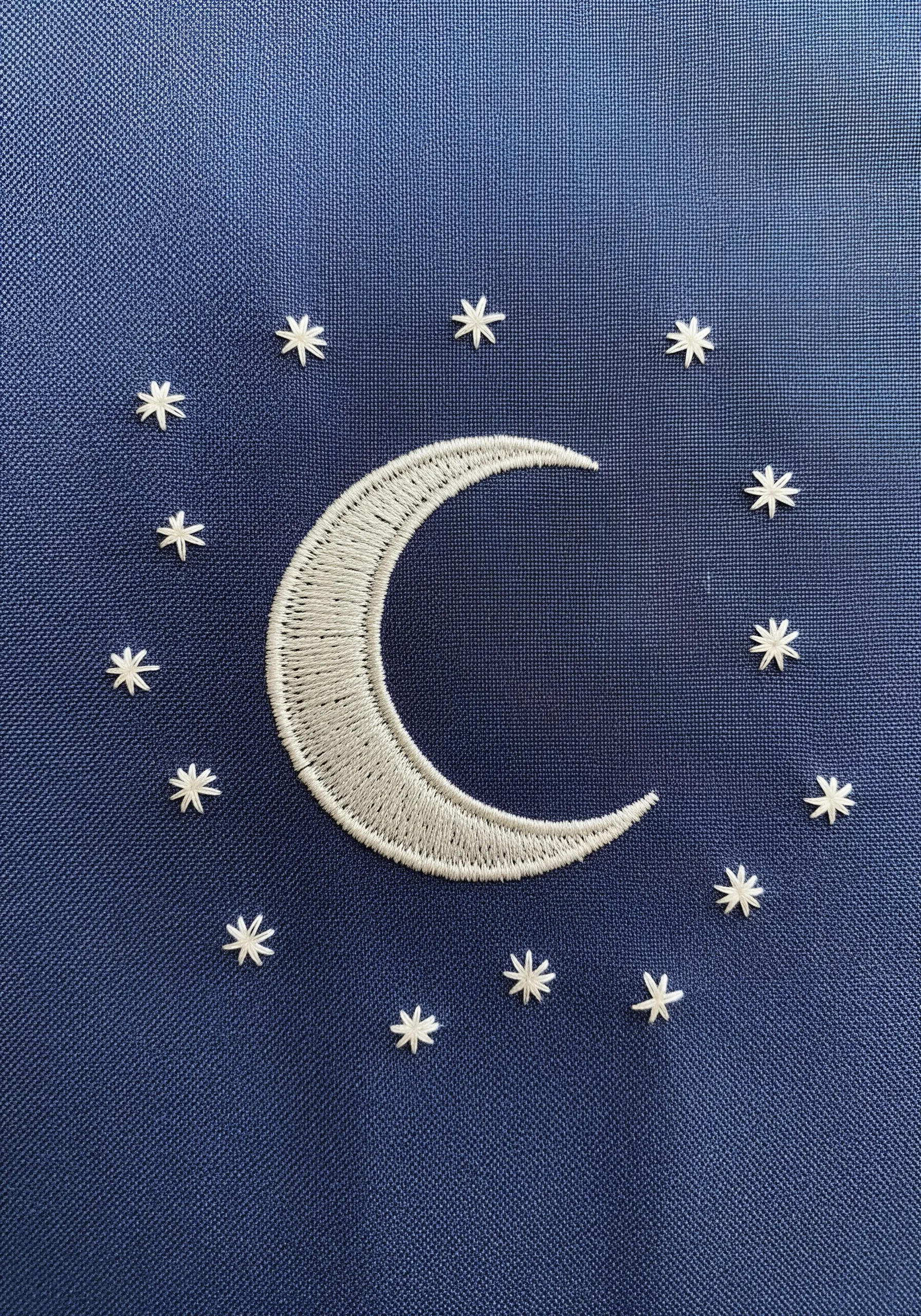 White crescent moon and stars embroidered on navy blue fabric