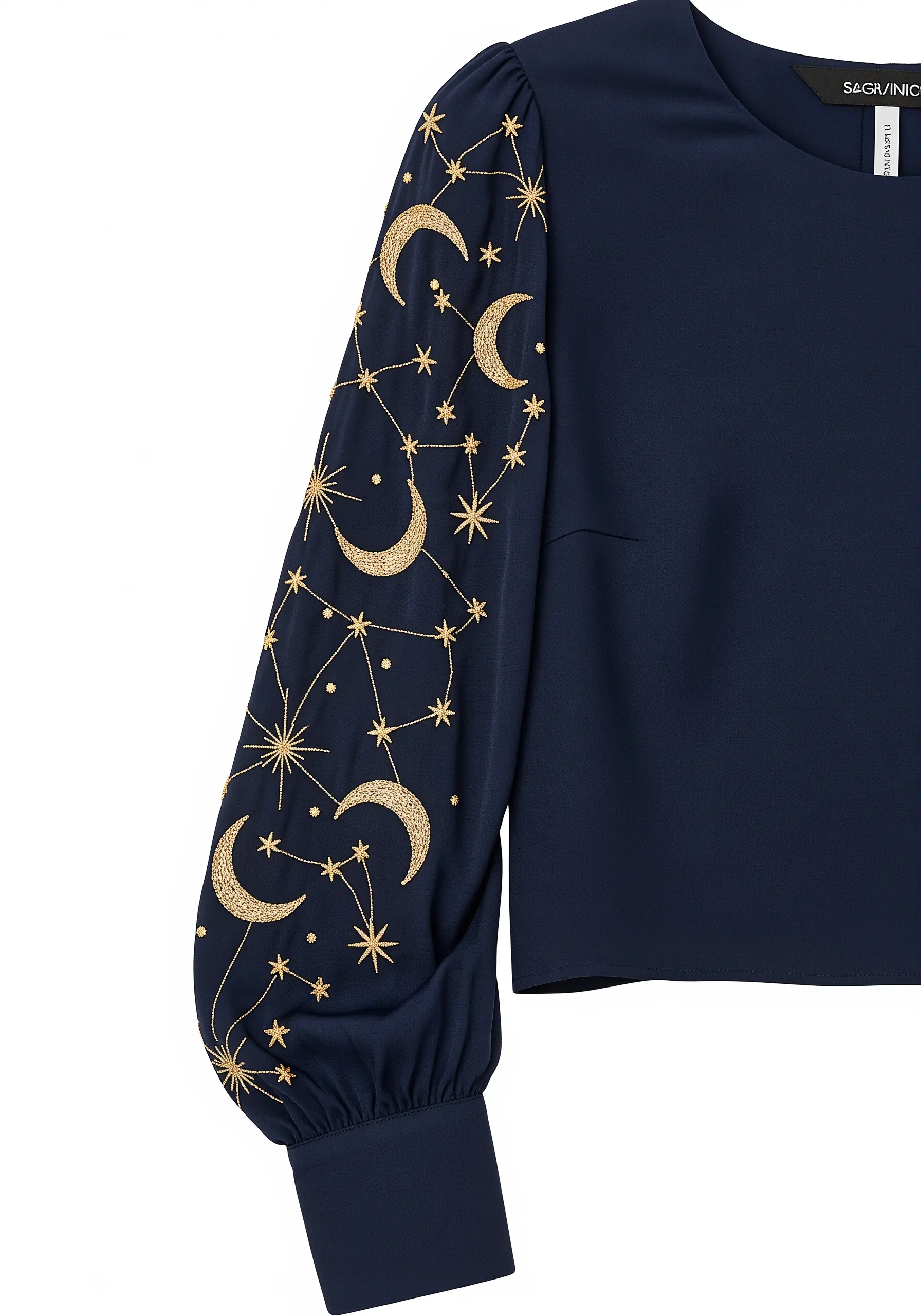 Gold metallic thread embroidery of moons and constellations on a dark navy puff sleeve.