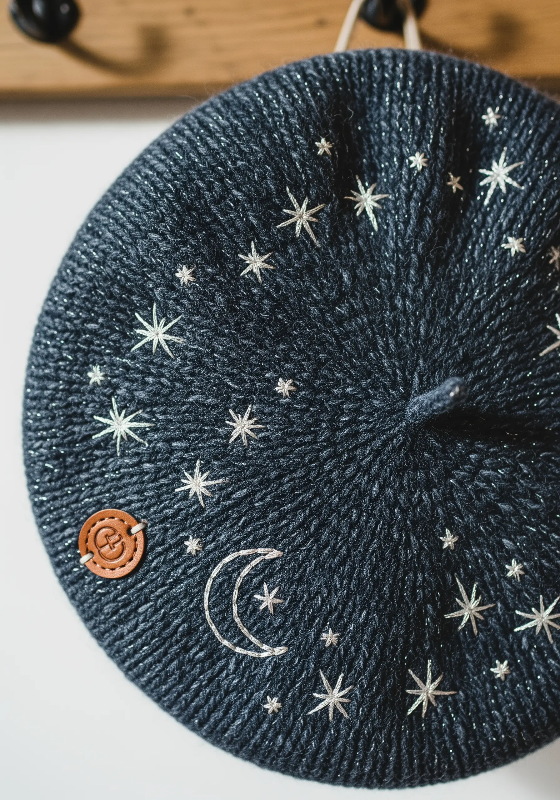 Dark blue knit beret with silver and white stars and a moon embroidered on top