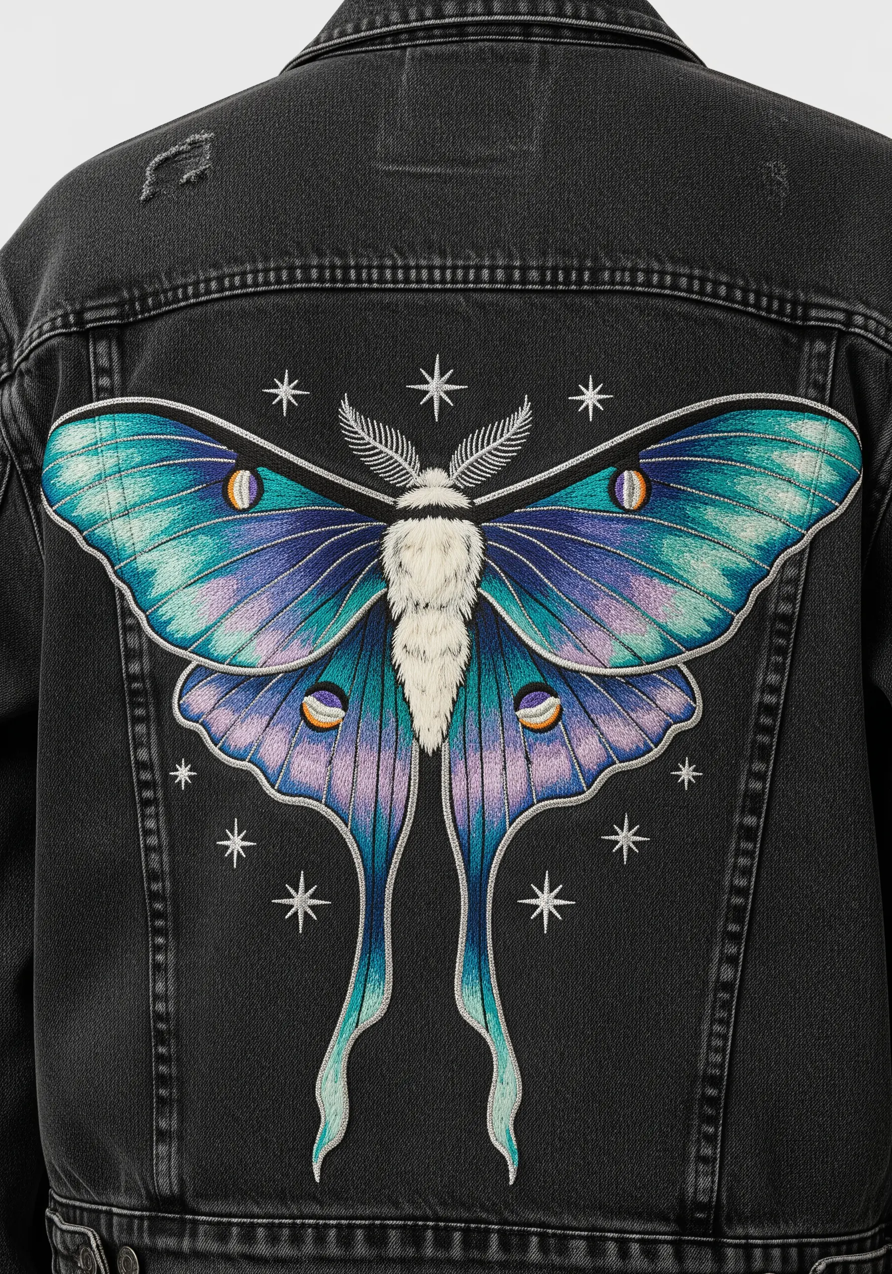 Embroidered luna moth with gradient teal and purple wings on a black denim jacket.