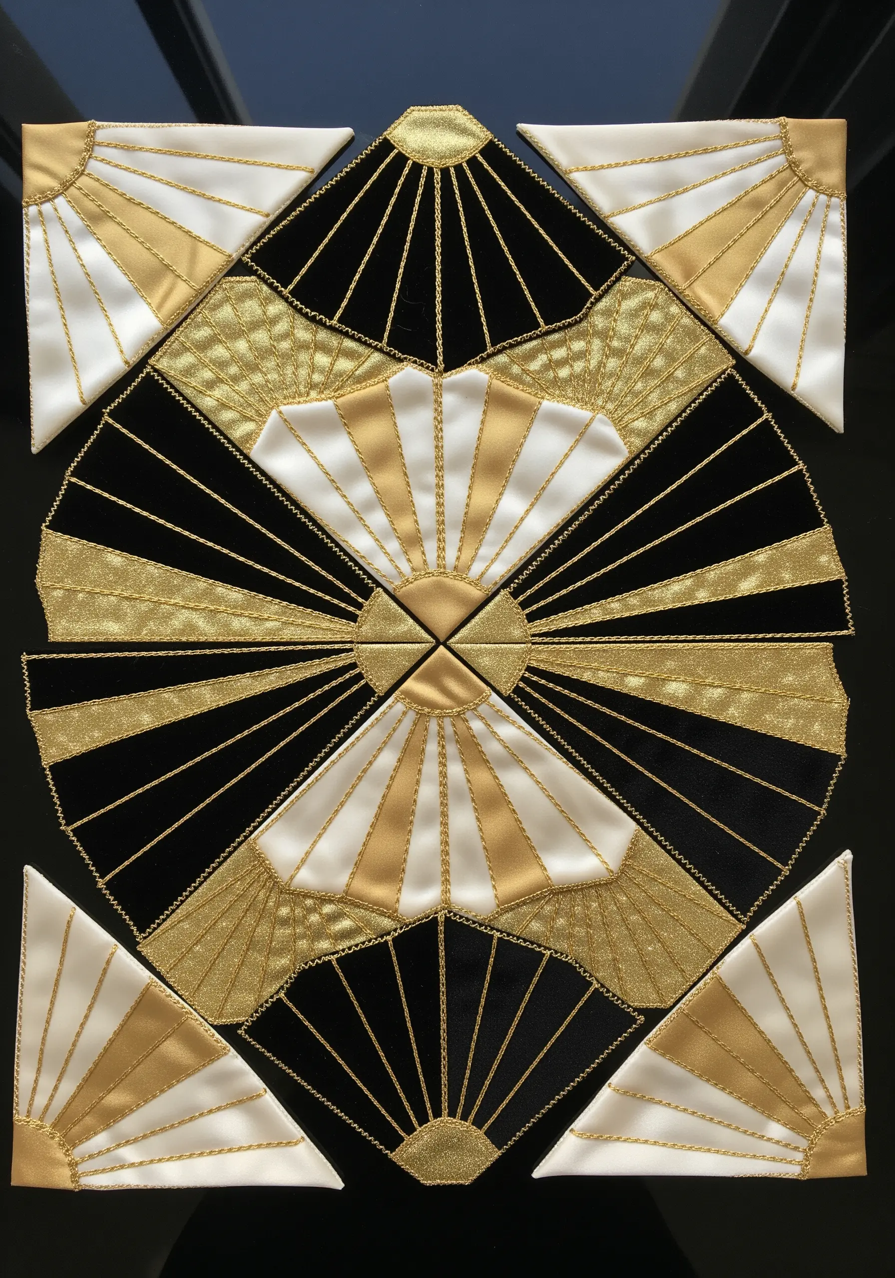 An Art Deco-inspired collage with black, white, and gold fabrics arranged in a symmetrical sunburst pattern.