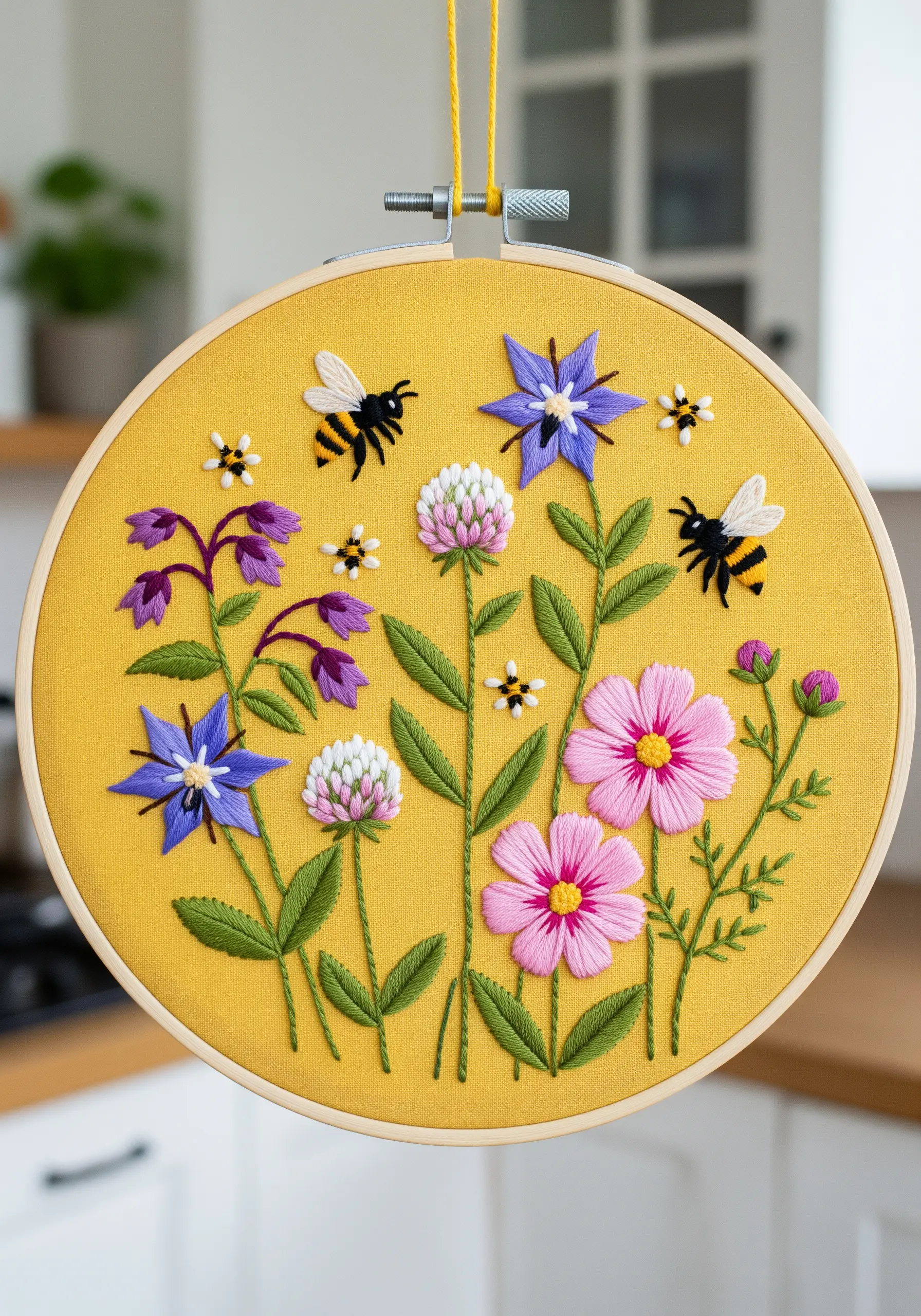 Embroidery of bees and colorful wildflowers on a bright yellow fabric background.