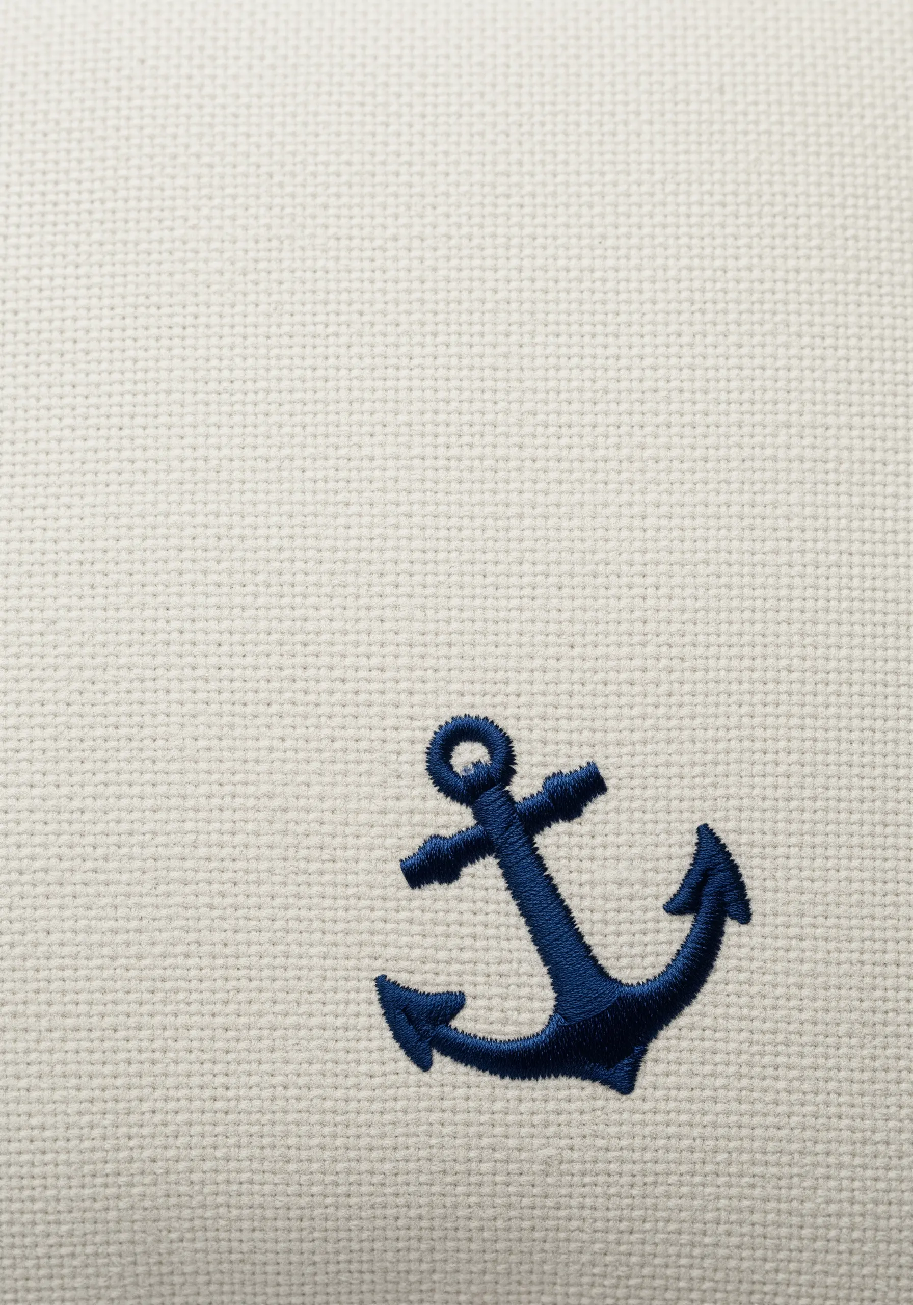 A solid navy blue anchor with a satin stitch fill on a cream canvas fabric.