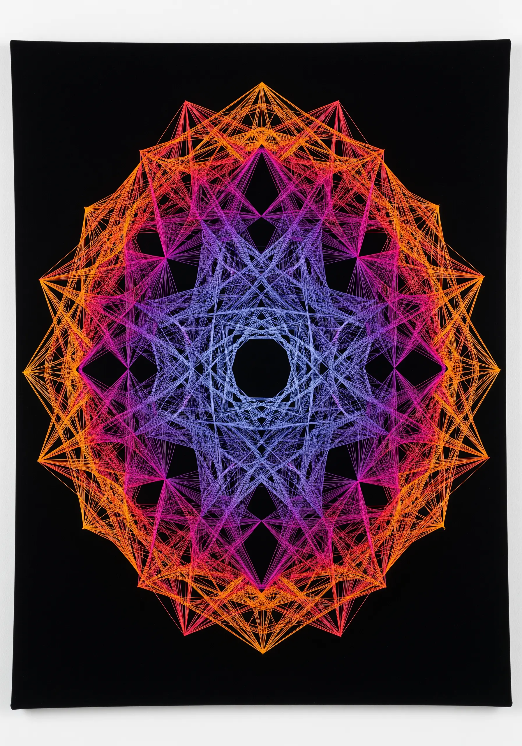 A complex geometric mandala with a vibrant color gradient from orange to blue on black fabric.